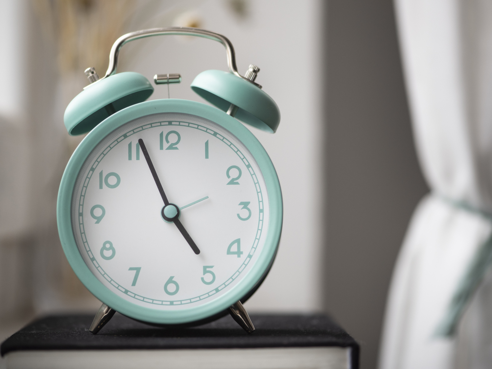 Голубой будильник стоит на книге в комнате