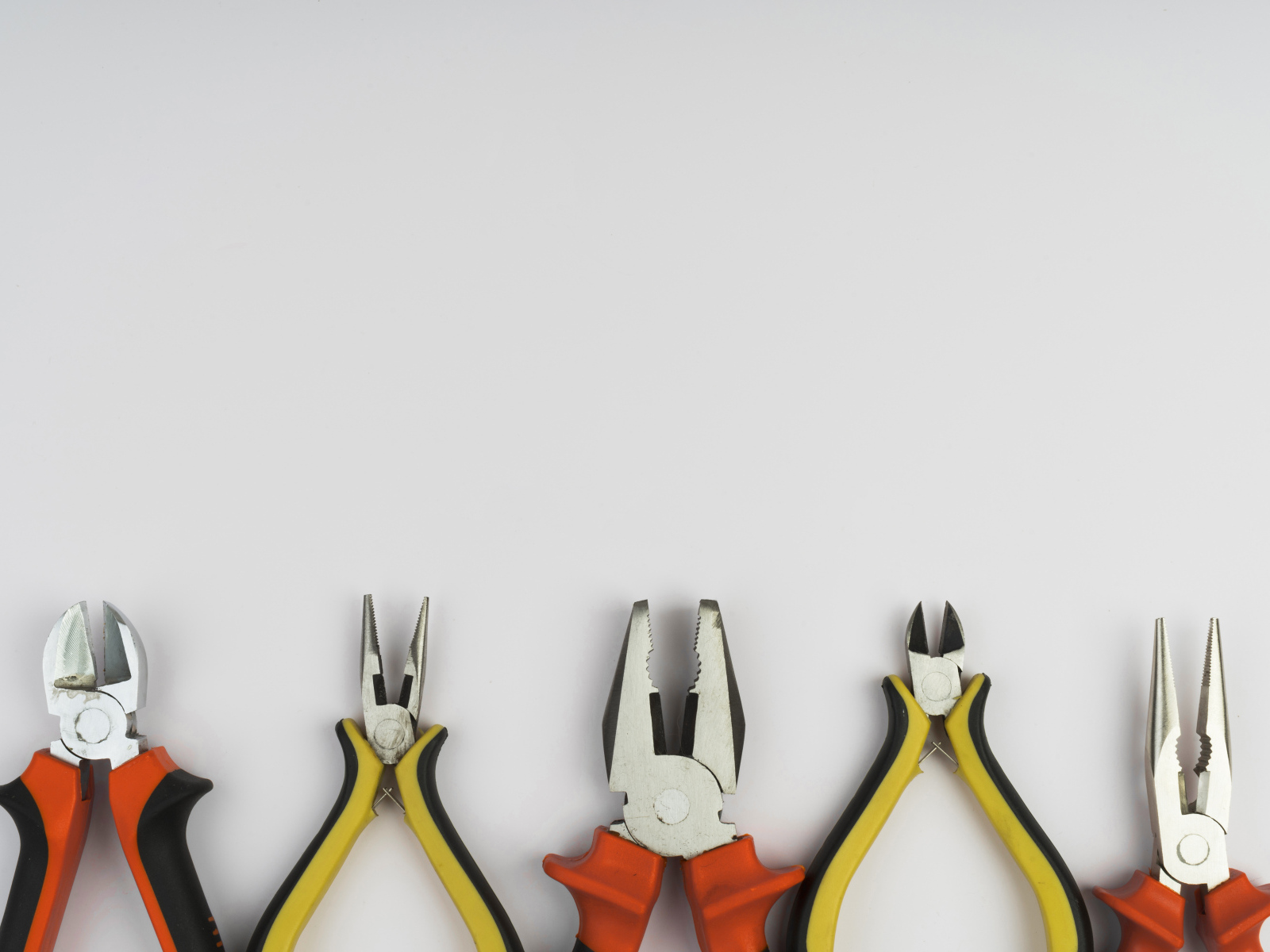 Разные плоскогубцы на сером фоне