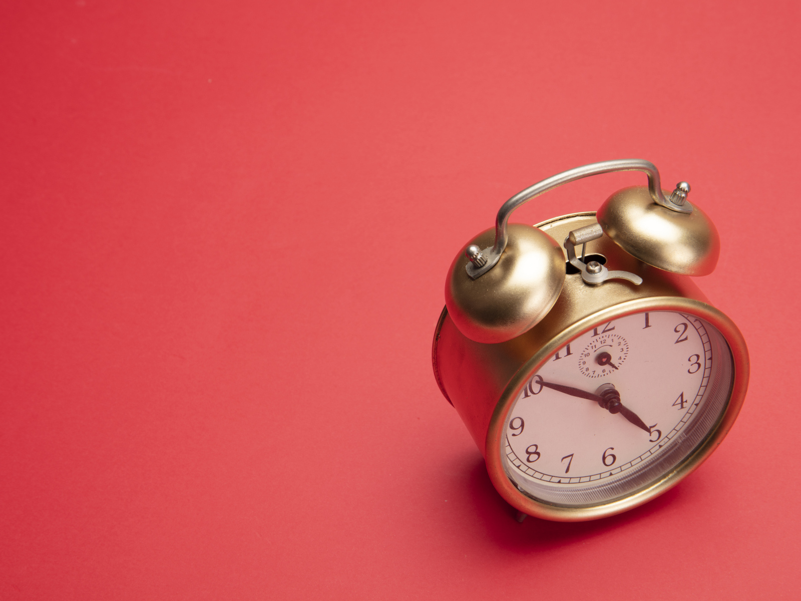 Золотой будильник на красном фоне