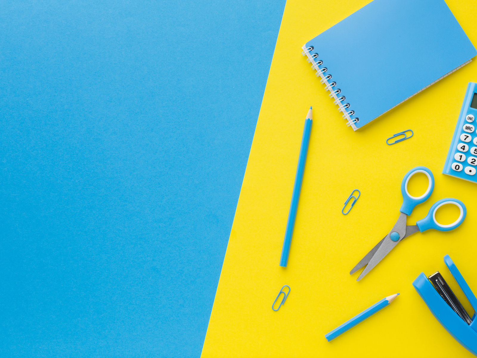 Блокнот, степлер, калькулятор, карандаш и ножницы на голубо-желтом фоне