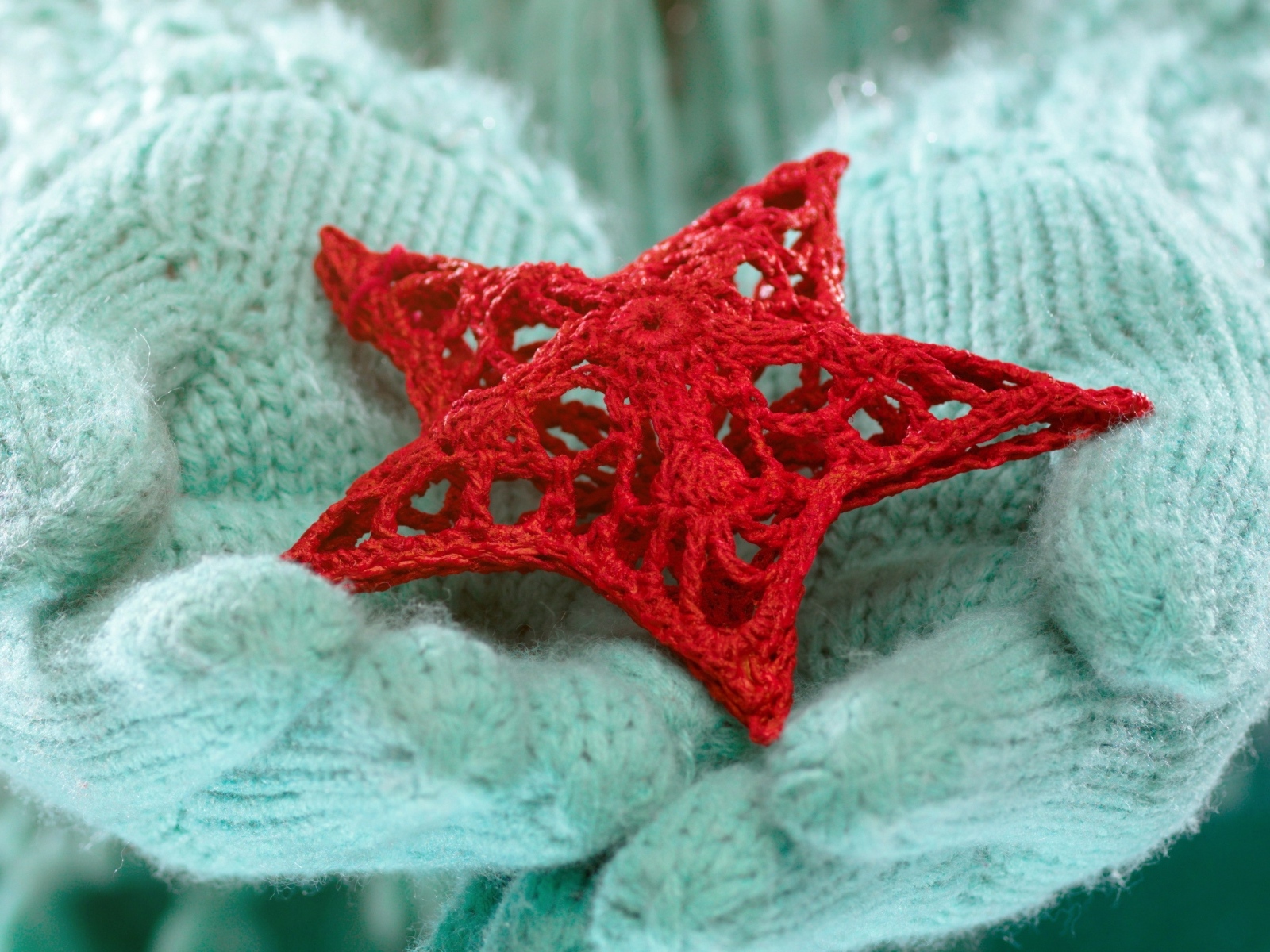 Красная вязаная звезда в руках в варежках