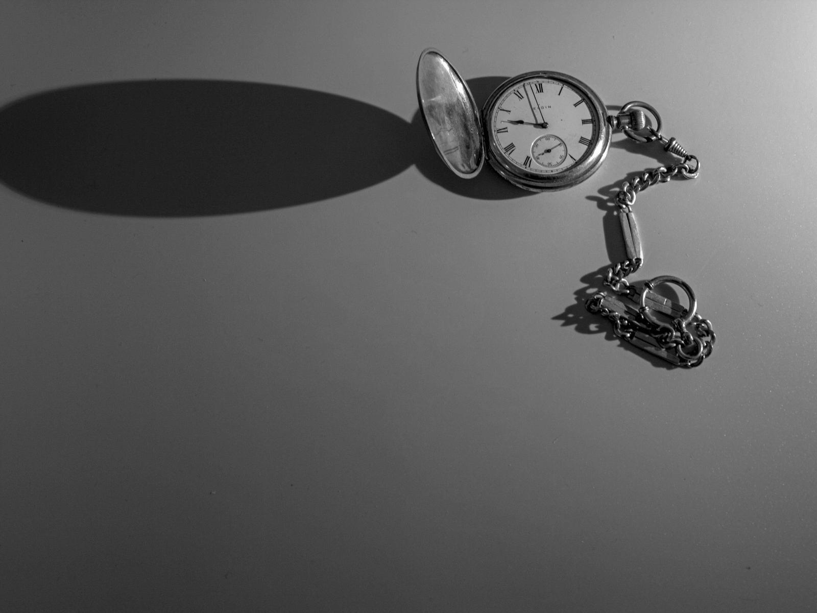 Тень от карманных часов на сером фоне