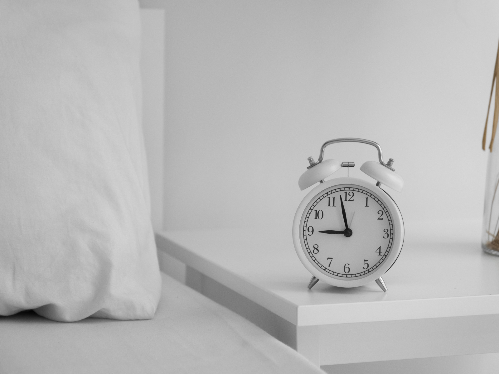Будильник стоит на тумбочке у кровати 