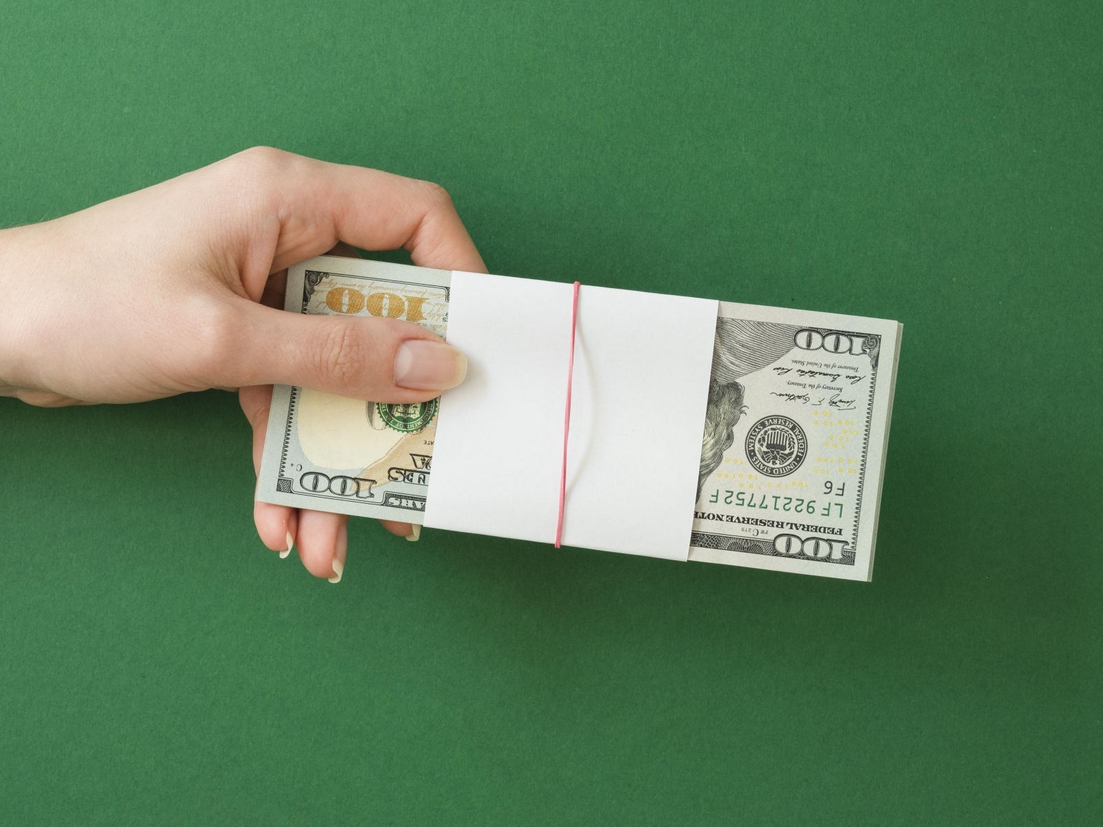 Пачка денег в руке у девушки на зеленом фоне