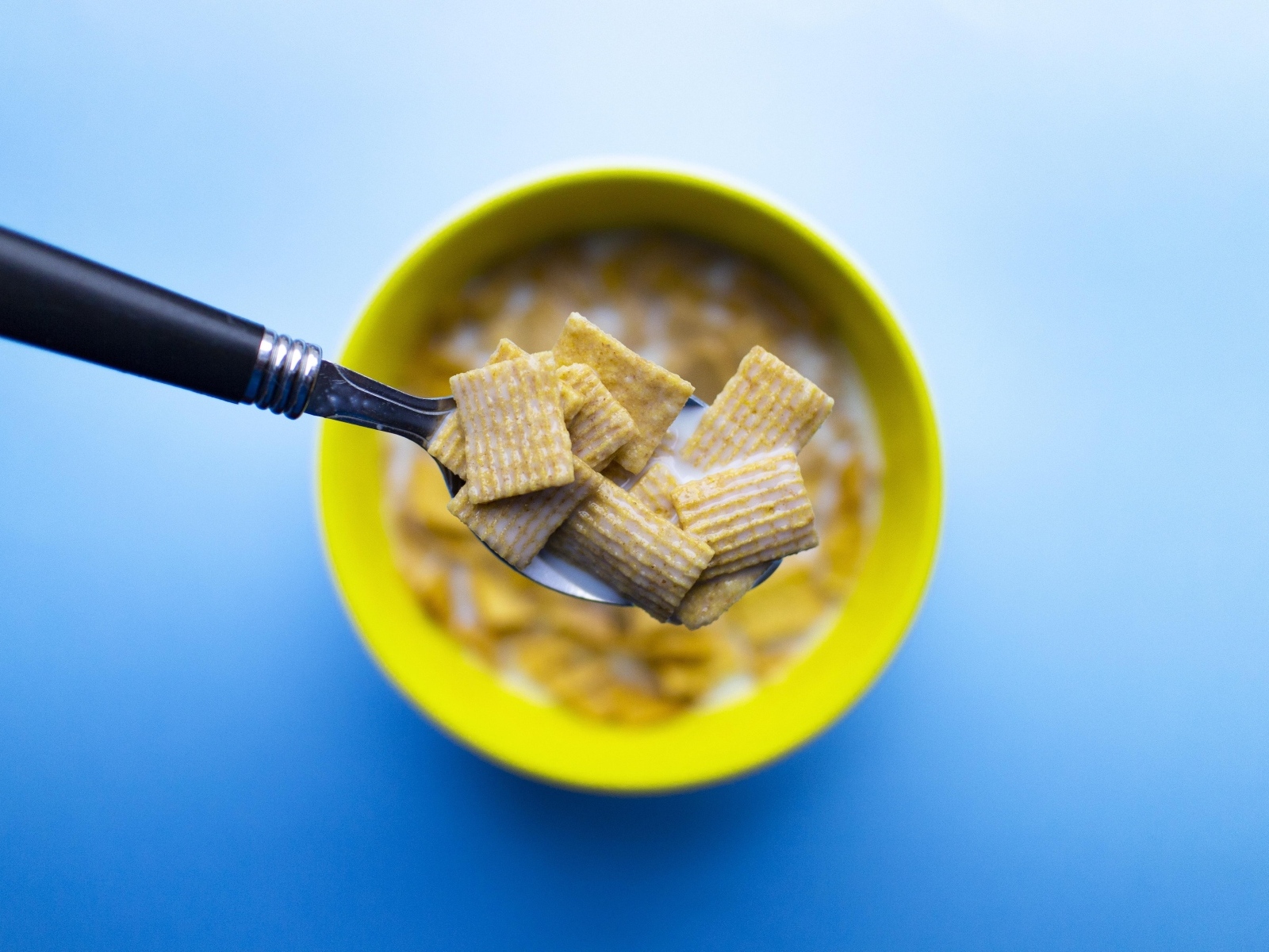 Хлопья с молоком на ложке на голубом фоне