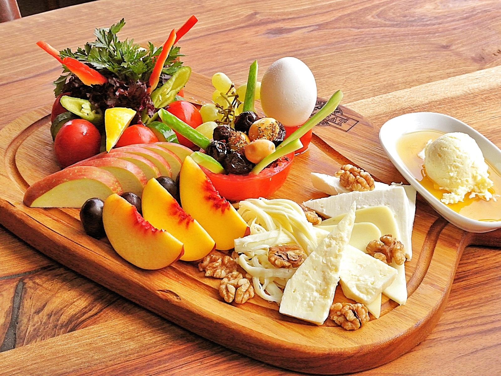 Сыр на доске с фруктами и салатом