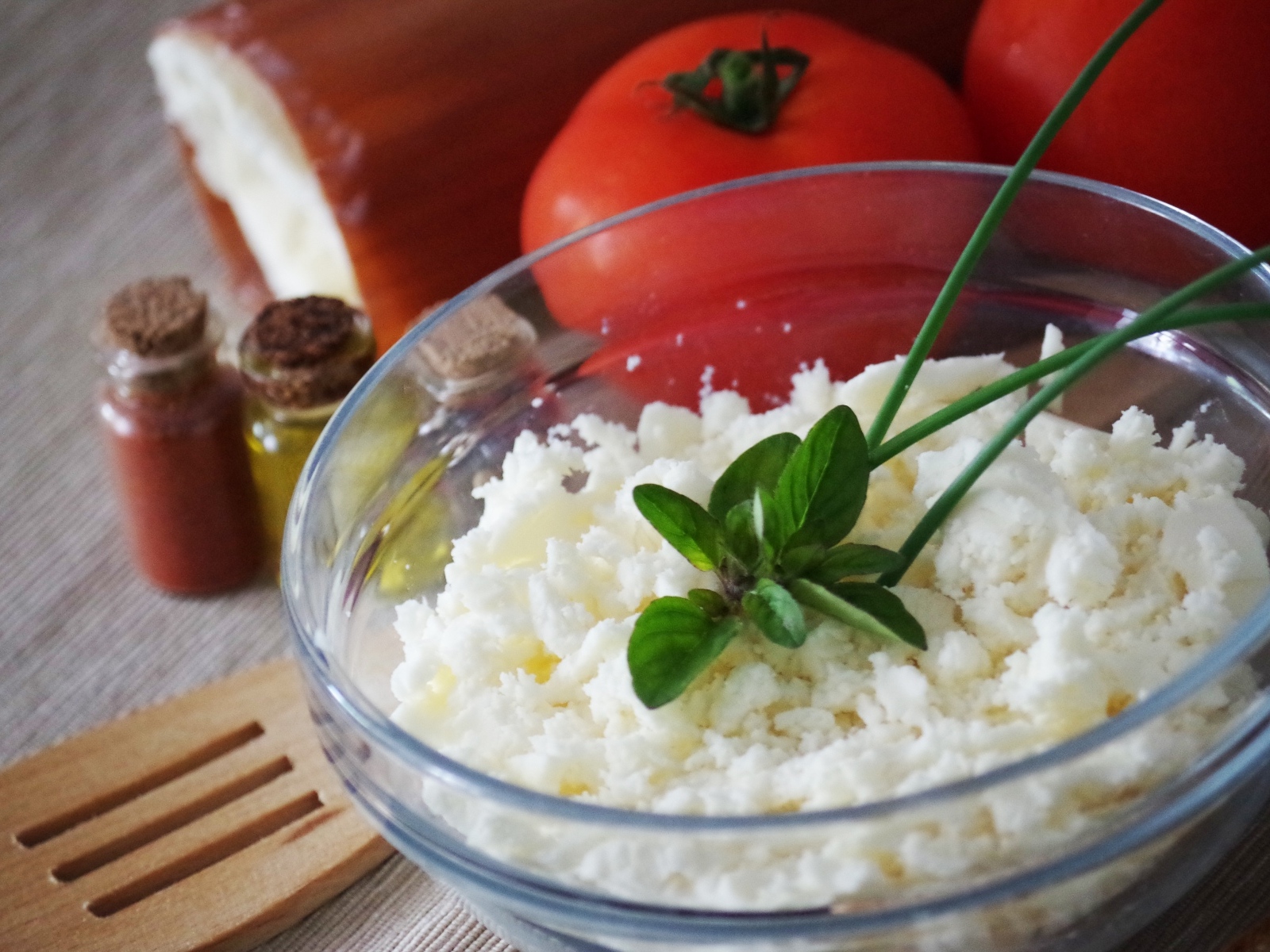 Творог в тарелке на столе с помидорами