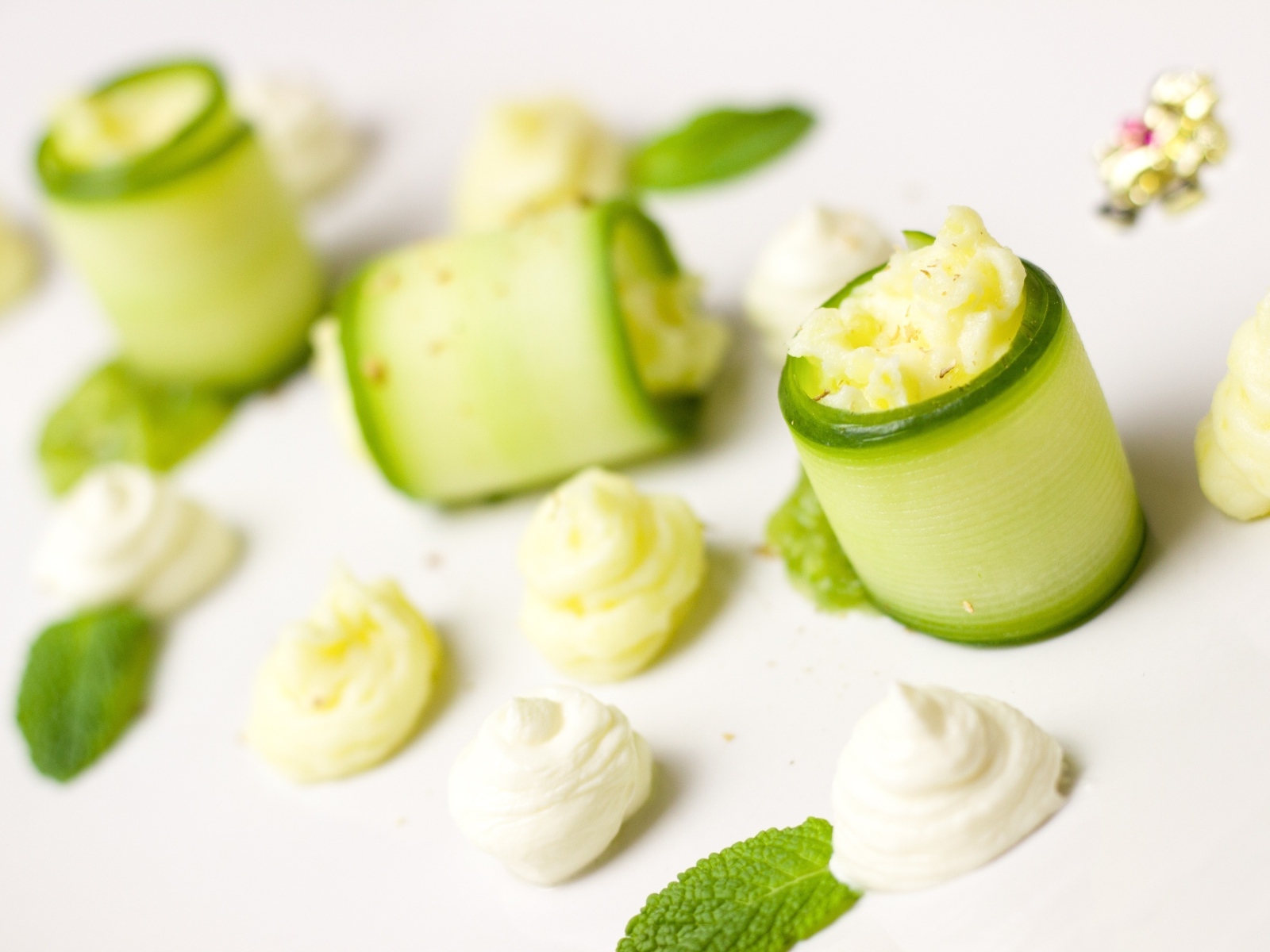 Рулетики из огурца с кремом на белом фоне