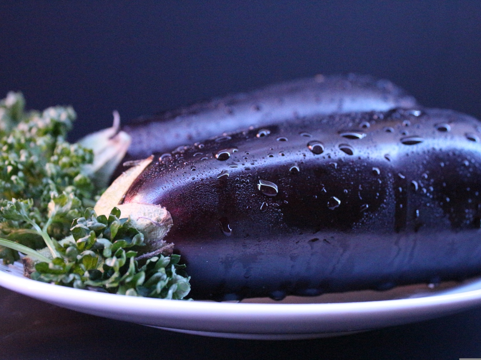 Два баклажана на тарелке с зеленью