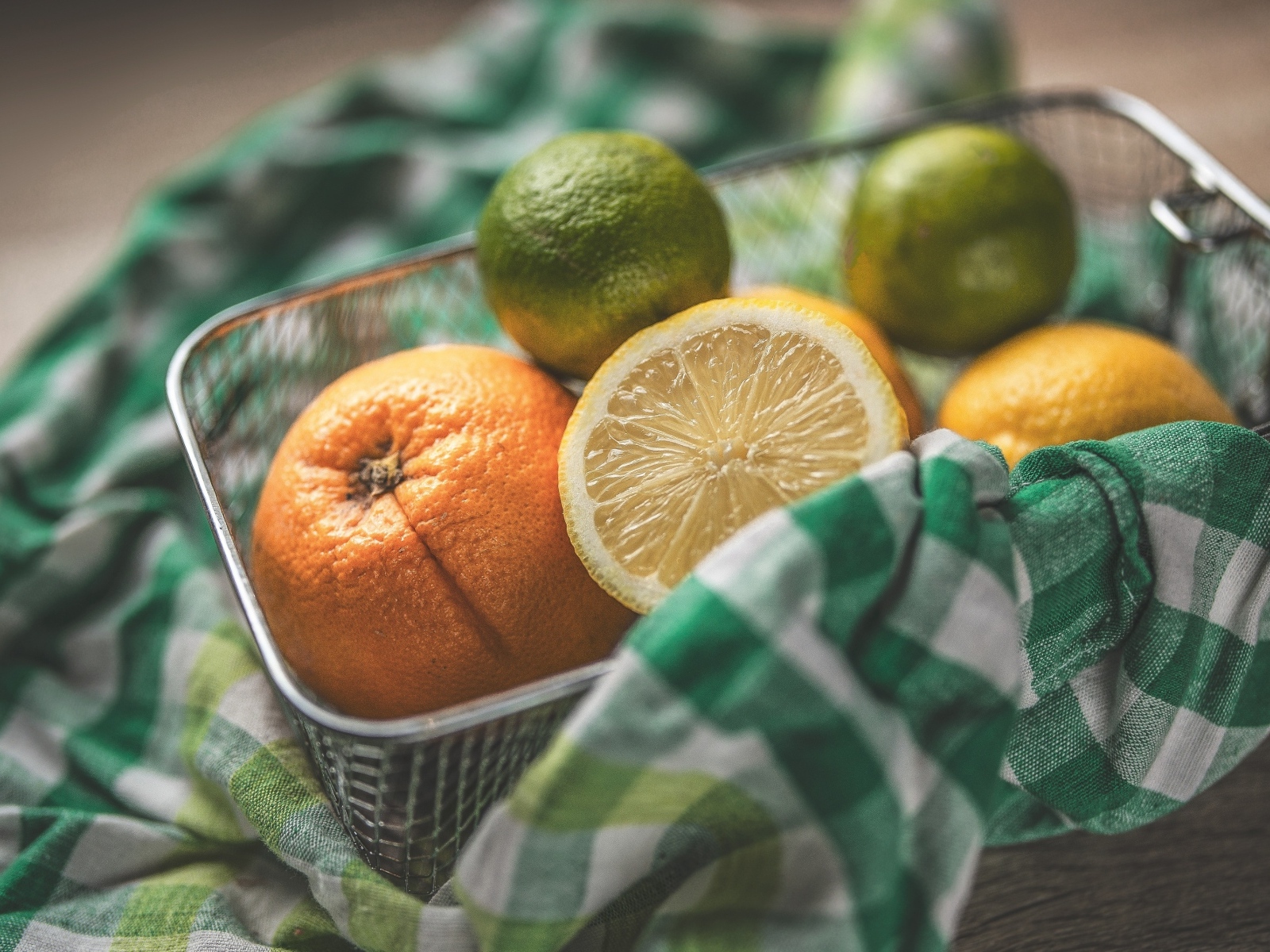 Цитрусовые фрукты в железной корзинке на столе