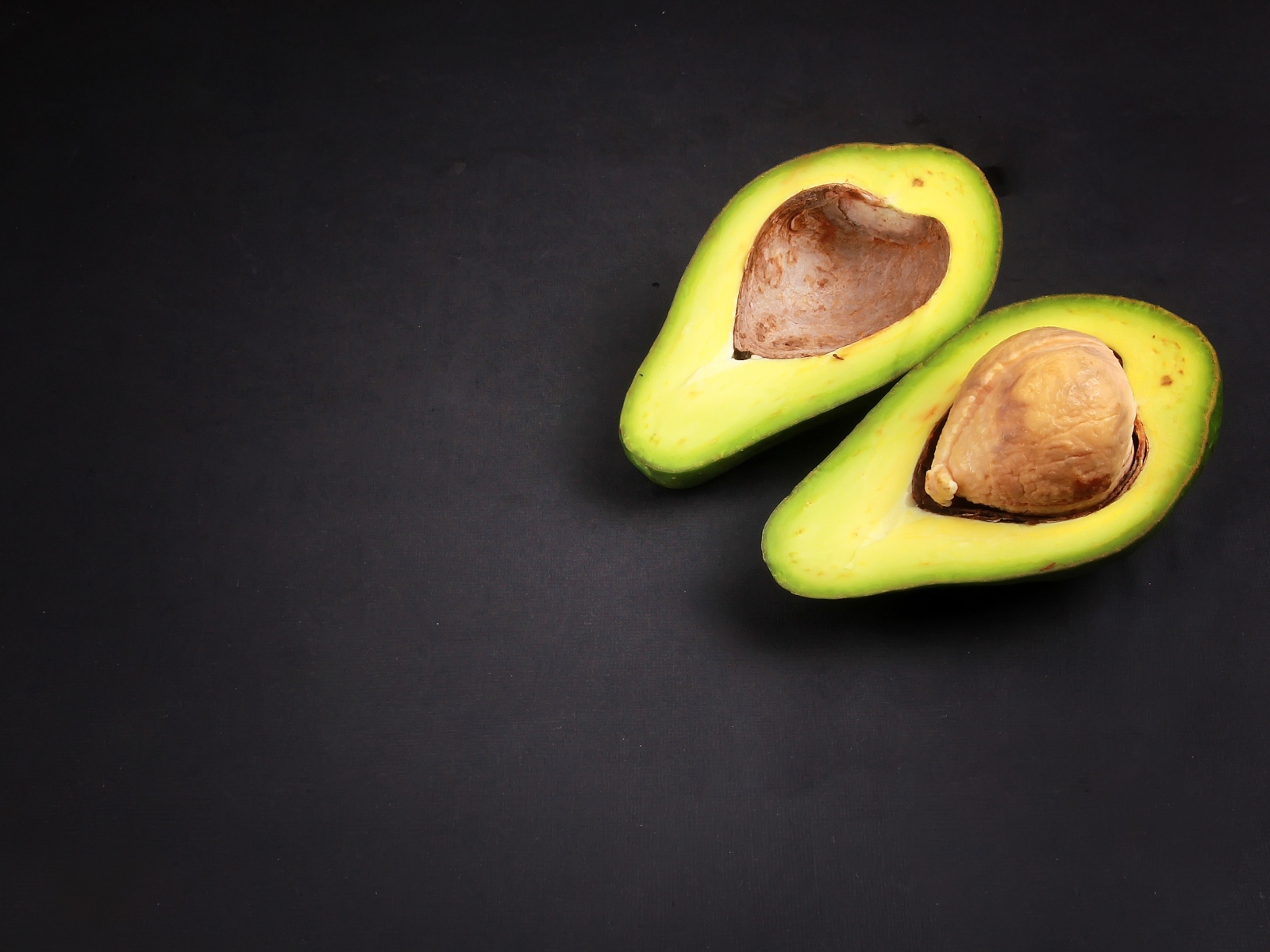 Свежий зеленый авокадо на черном фоне