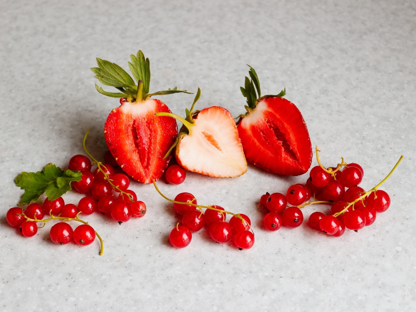 Ягоды клубники с красной смородиной на сером столе