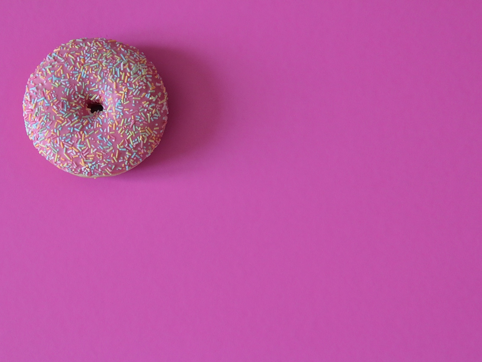 Аппетитный донат с глазурью на розовом фоне