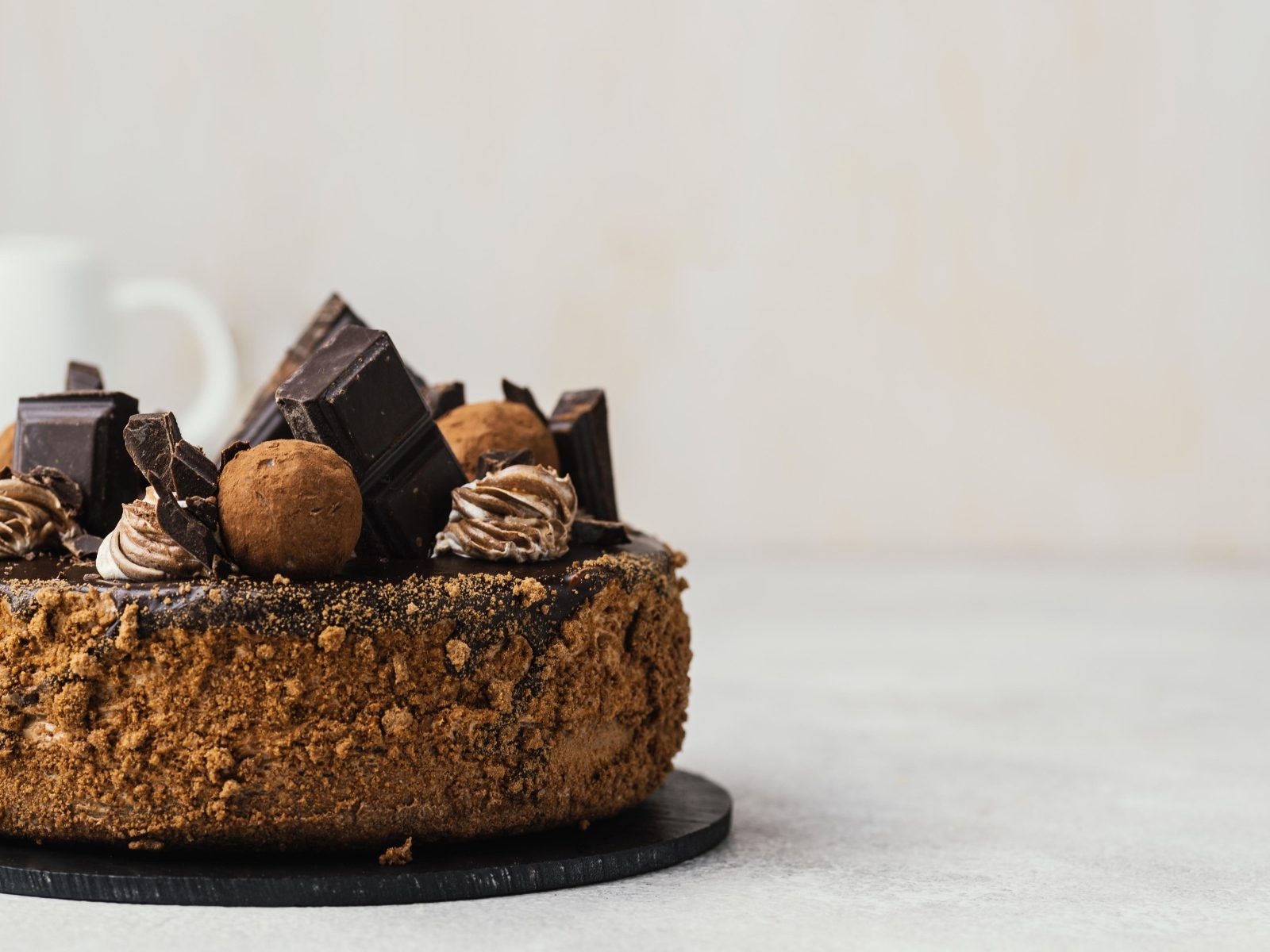 Торт украшен шоколадной глазурью и конфетами на сером фоне