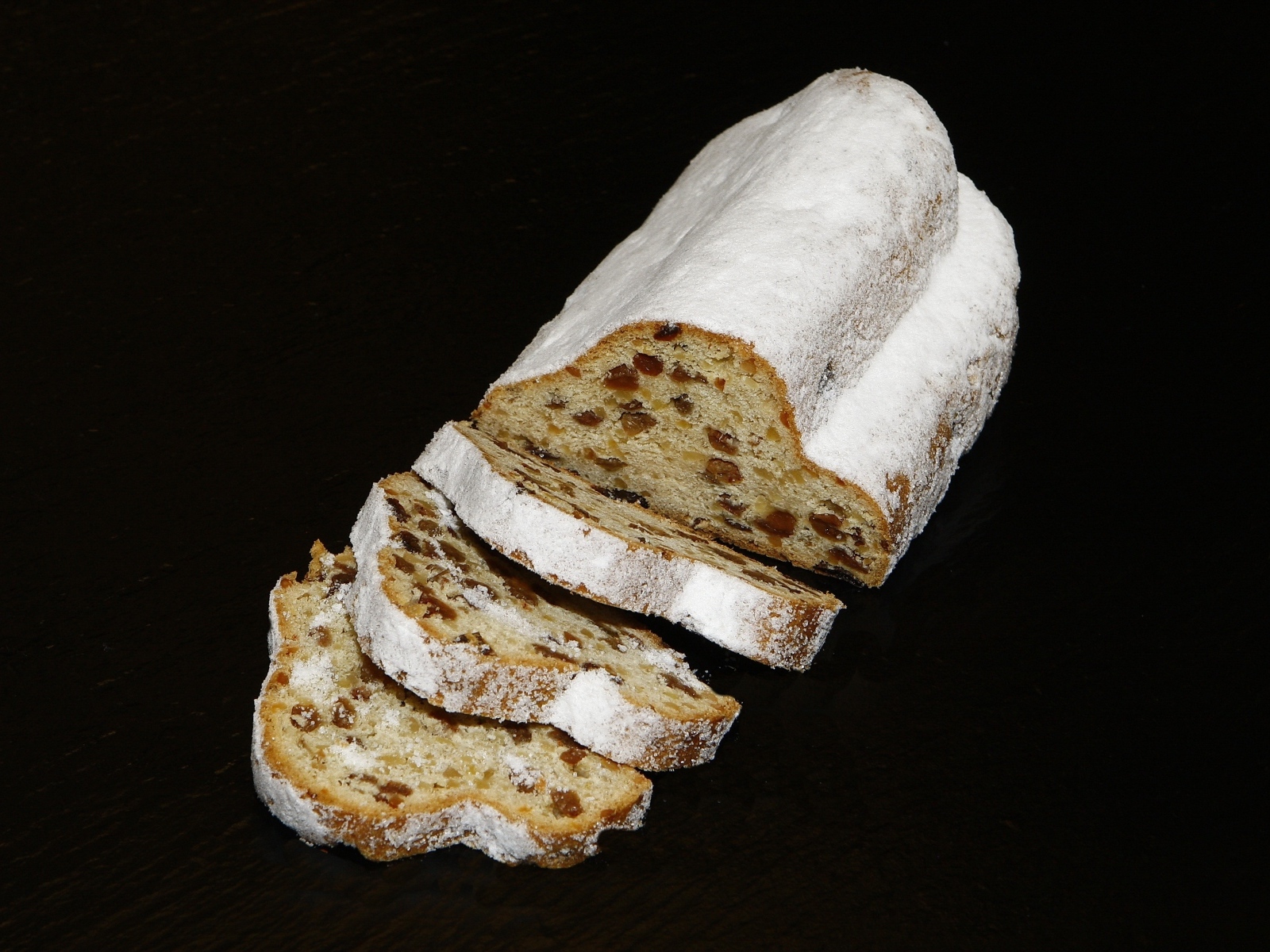 Кекс с сахарной пудре с изюмом на черном фоне