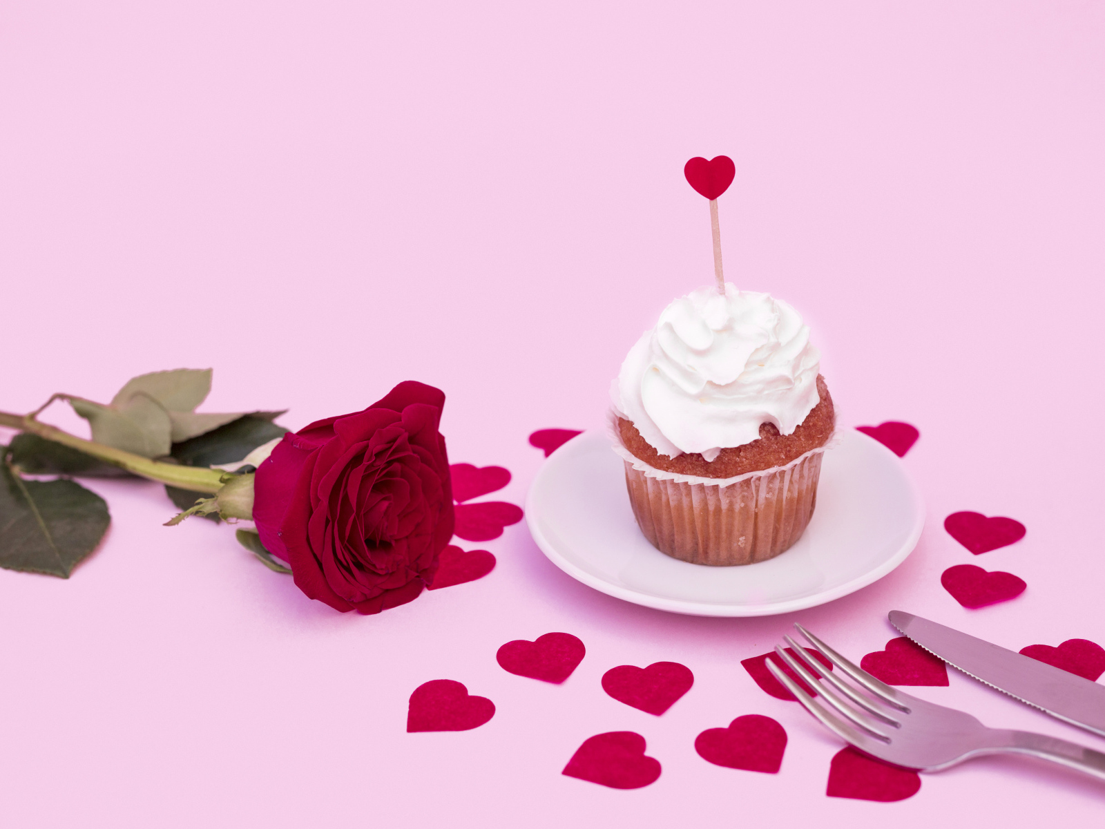Кекс с красной розой и сердечками на розовом фоне