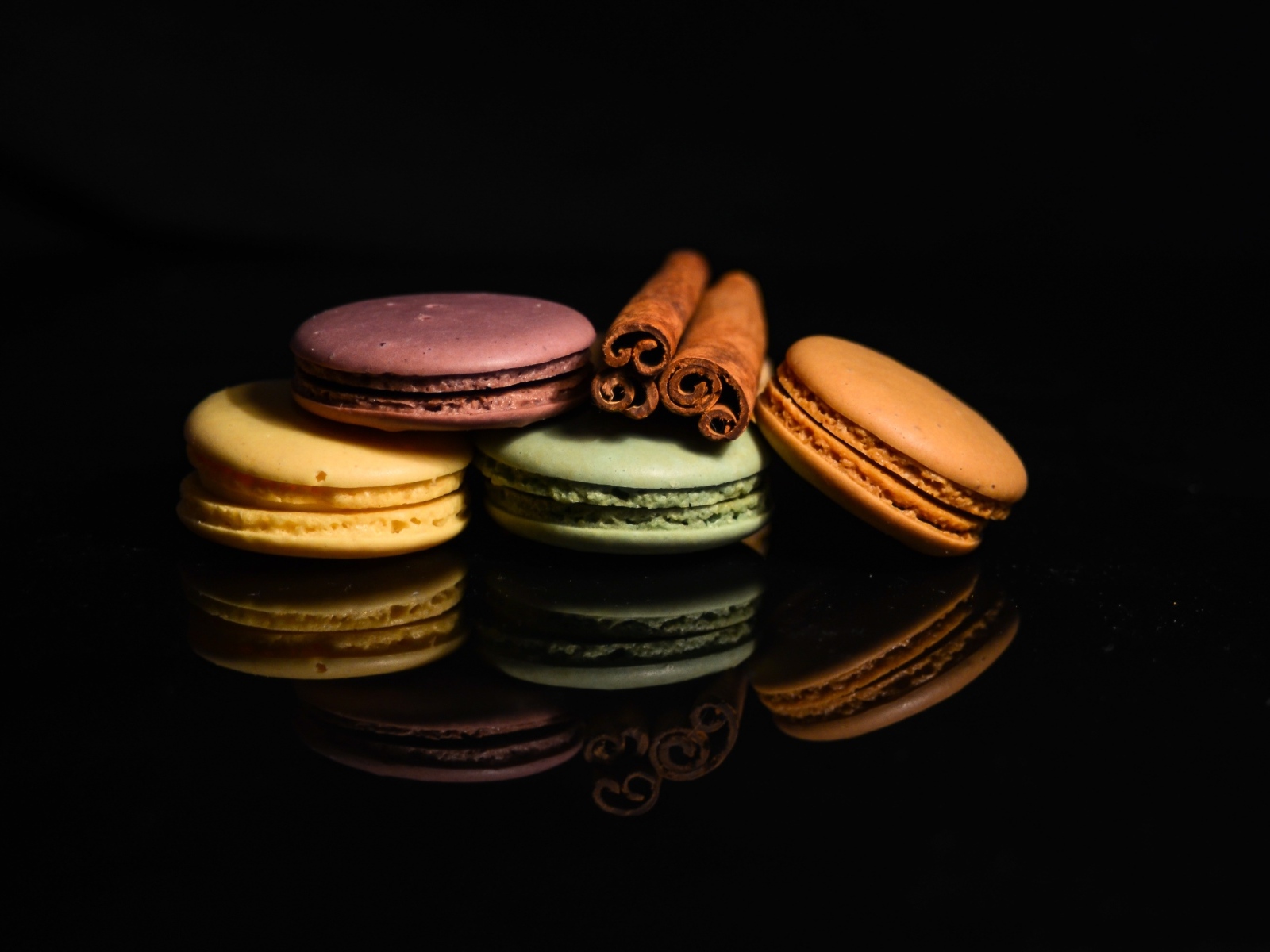 Десерт макарон с корицей на черном фоне