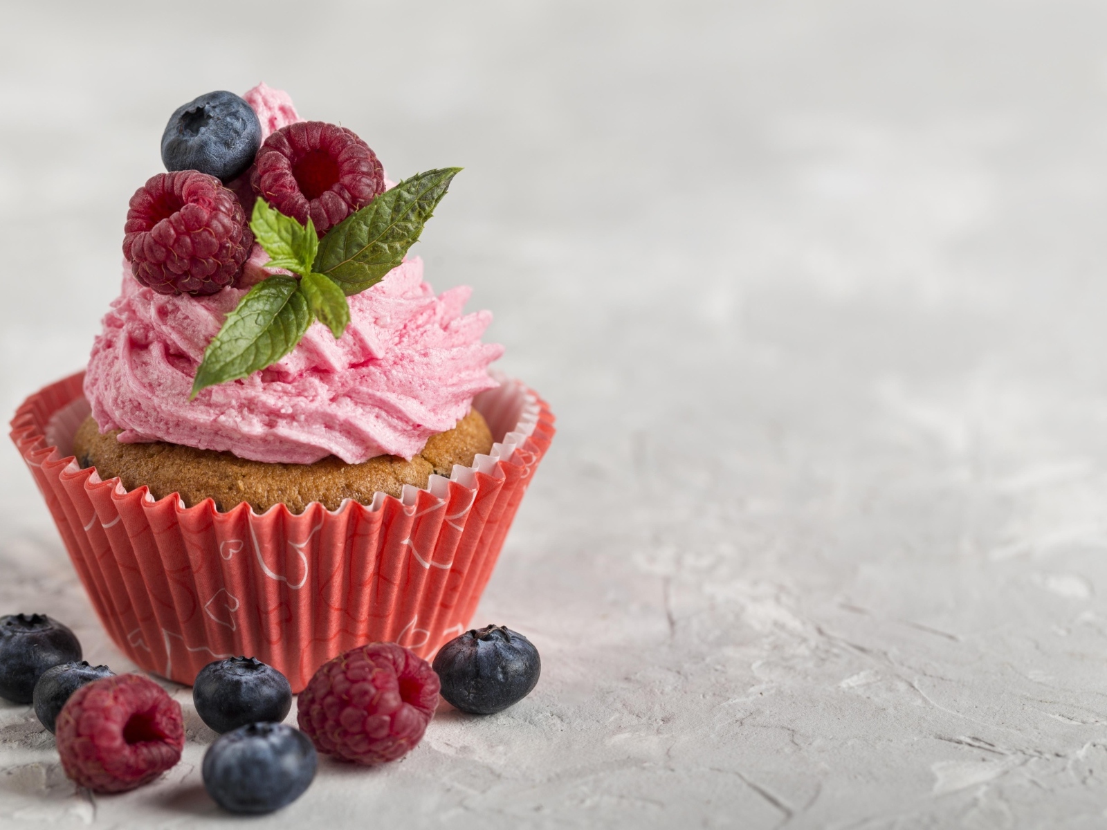 Маффин с розовым кремом и ягодами на столе