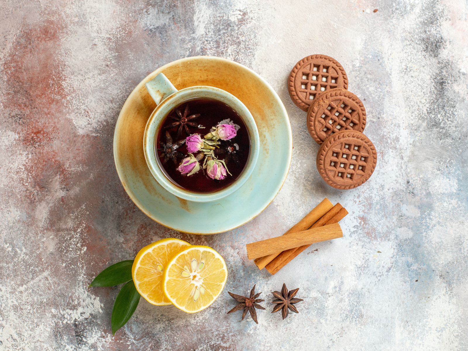 Чашка ароматного чая на столе с лимоном, печеньем и пряностями