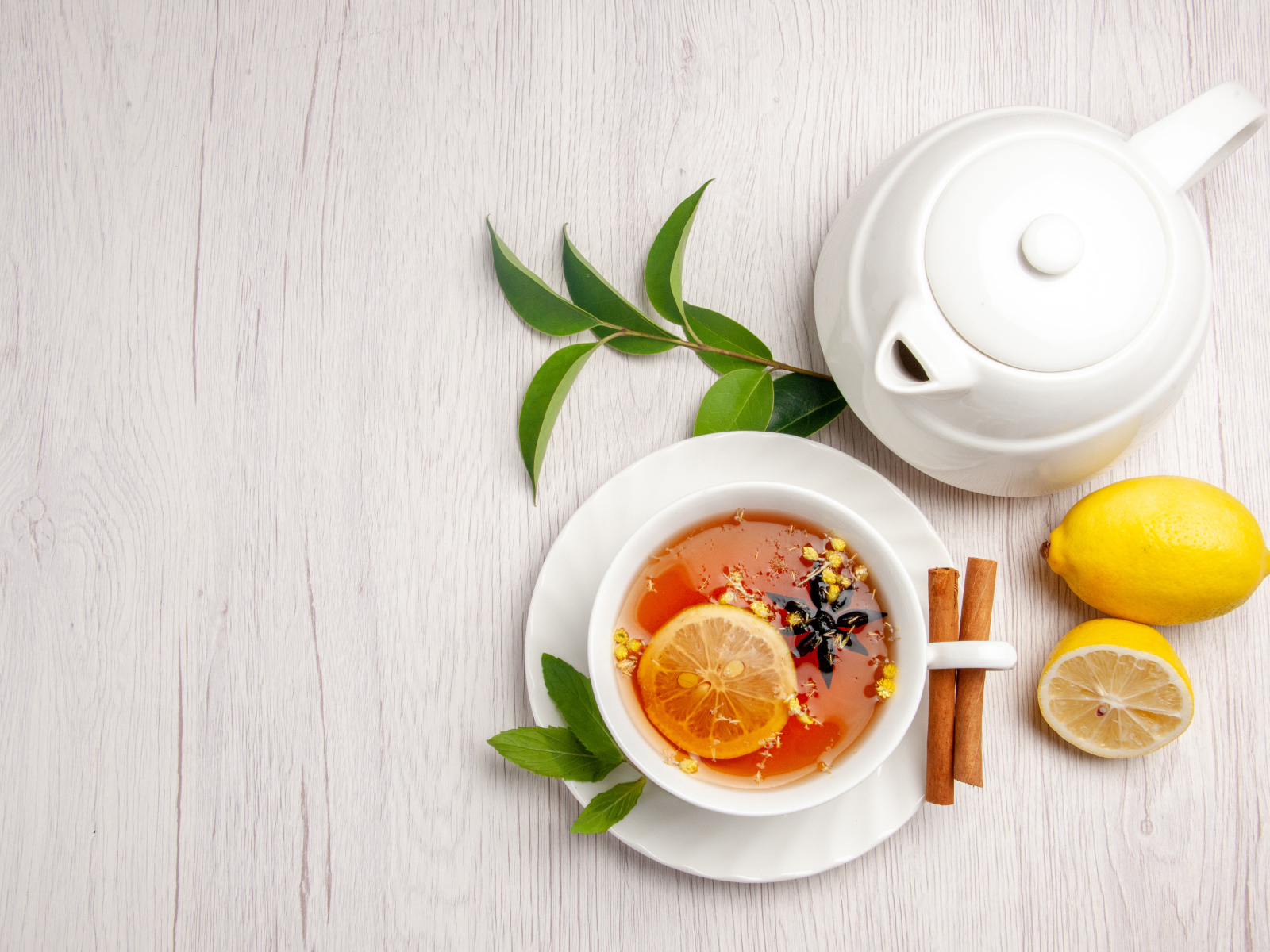 Вкусный чай в белой чашке на столе с лимоном и чайником