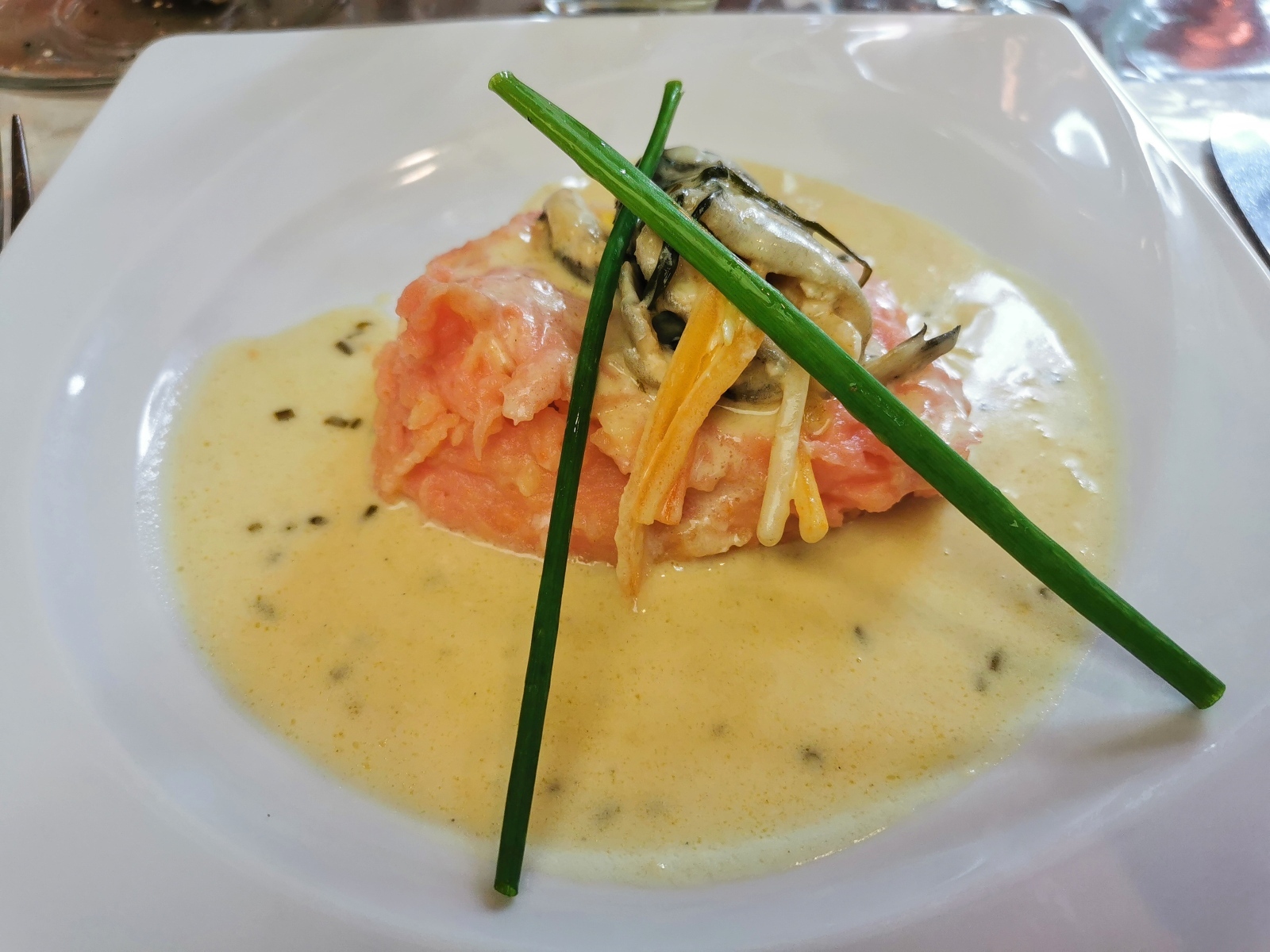 Красная рыба с соусом на тарелке с зеленым луком