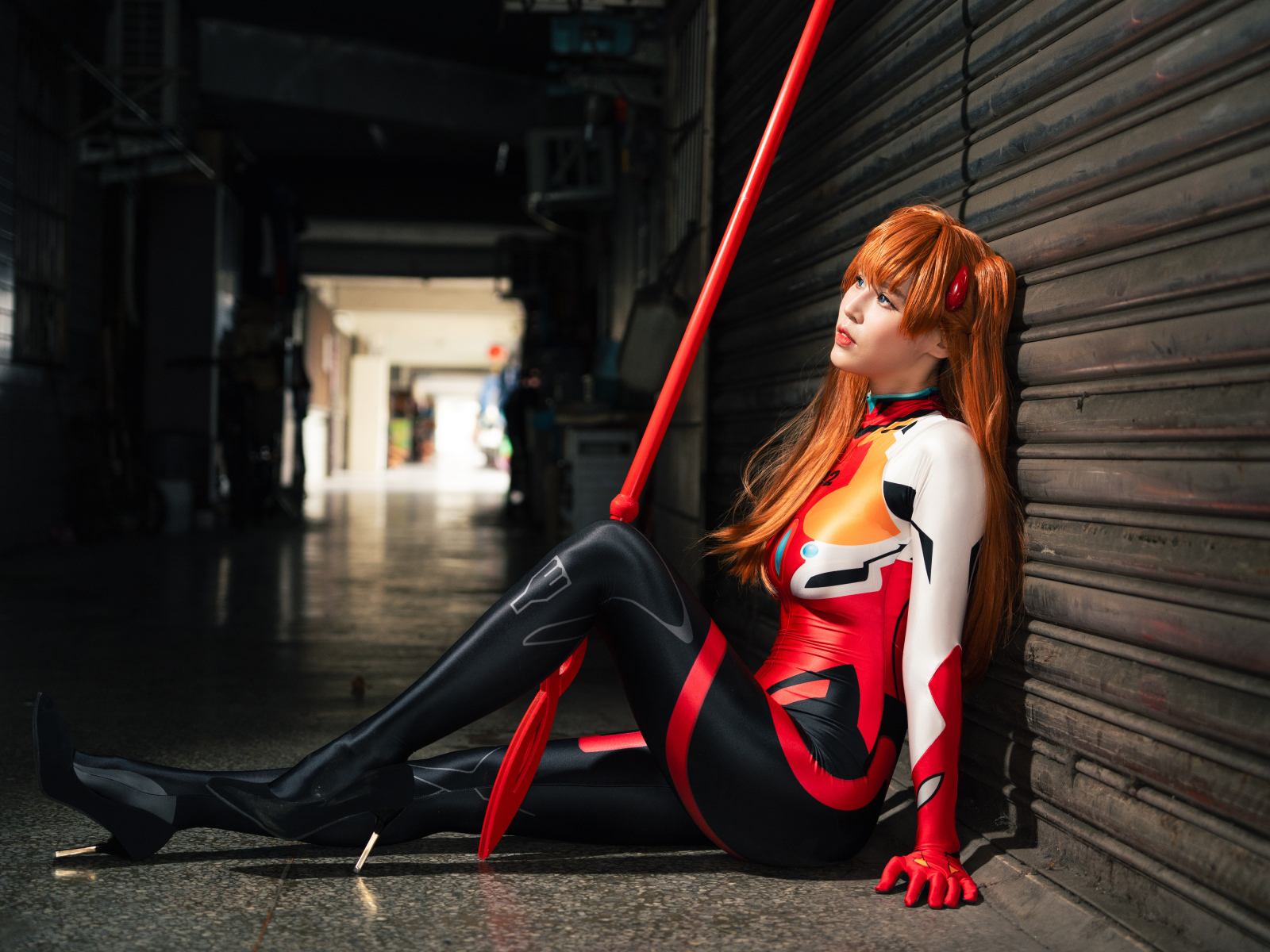 Девушка азиатка в костюме сидит у стены