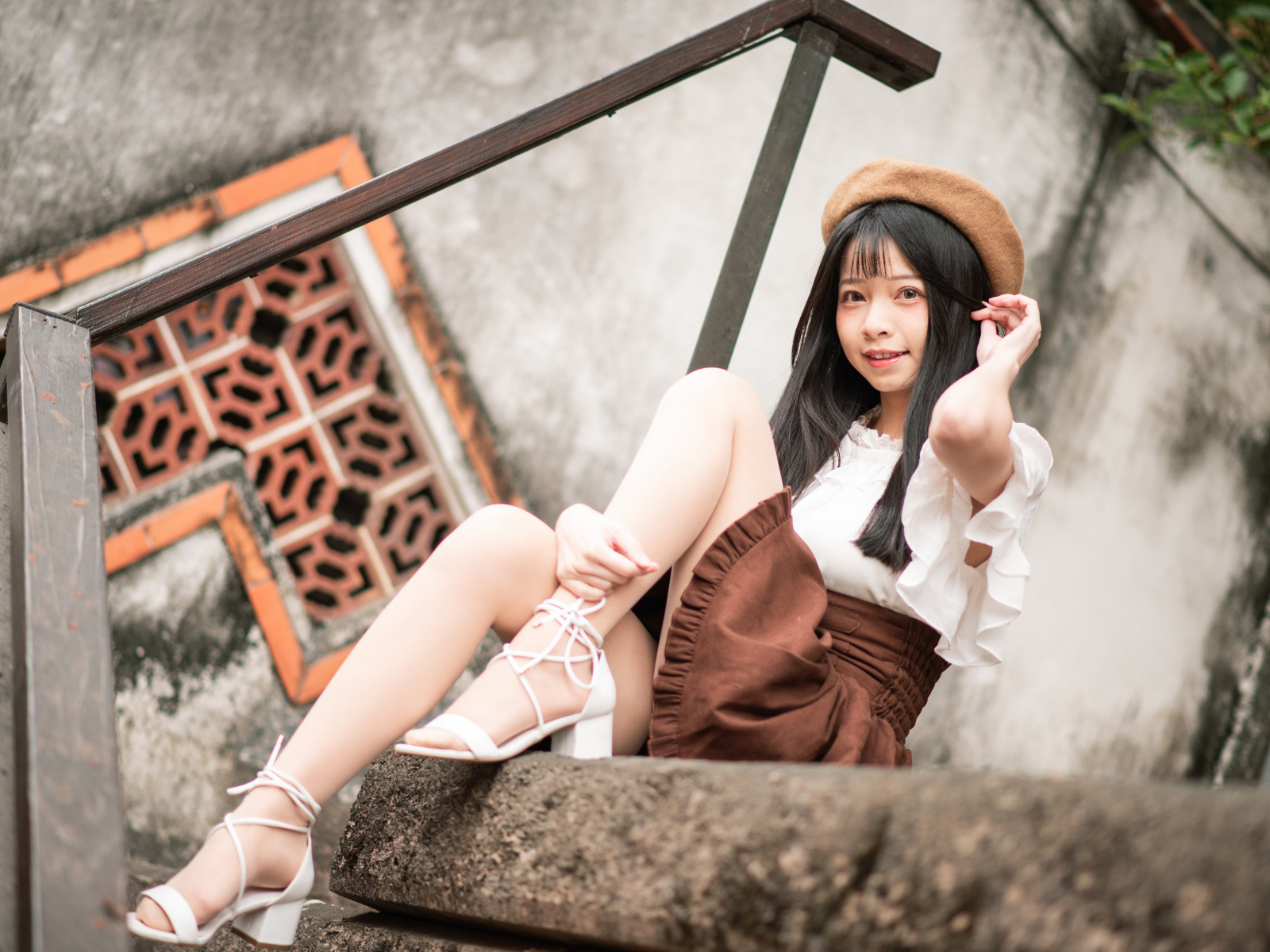 Девушка азиатка в белых туфлях сидит на ступеньках