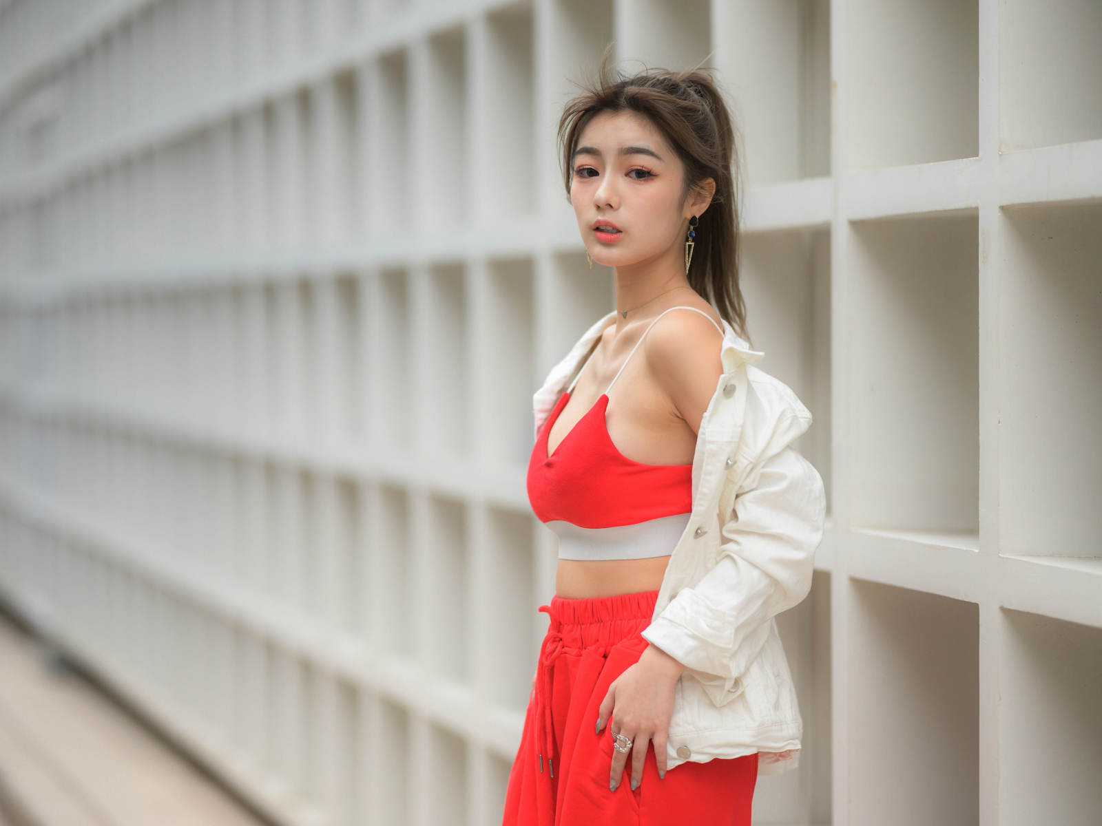 Азиатка в красном спортивном костюме стоит у стены