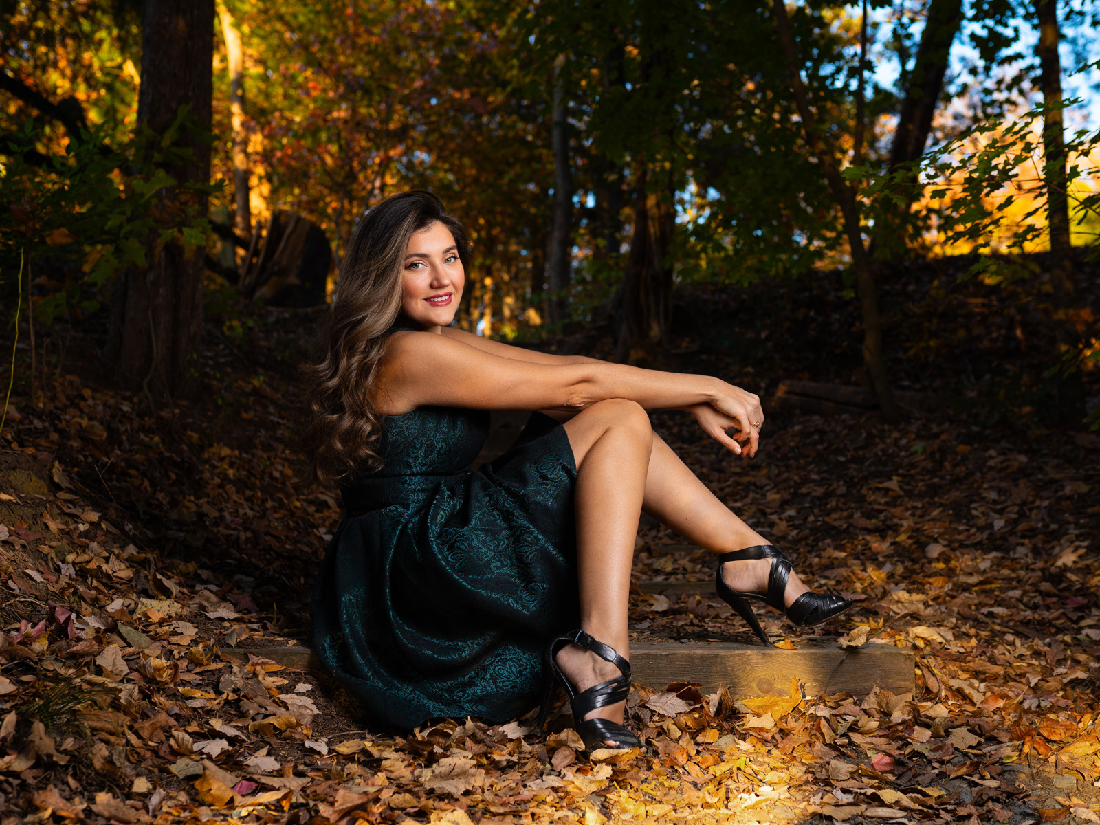 Красивая девушка в платье сидит на земле в осеннем парке