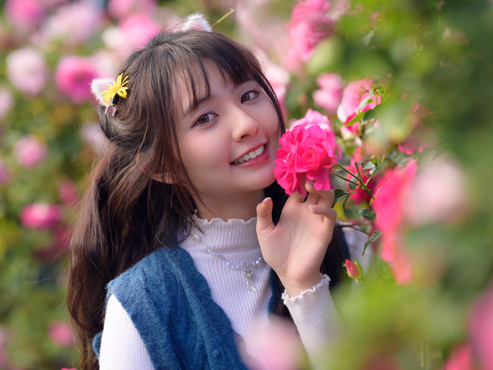Красивая улыбающаяся азиатка с розовым цветком розы