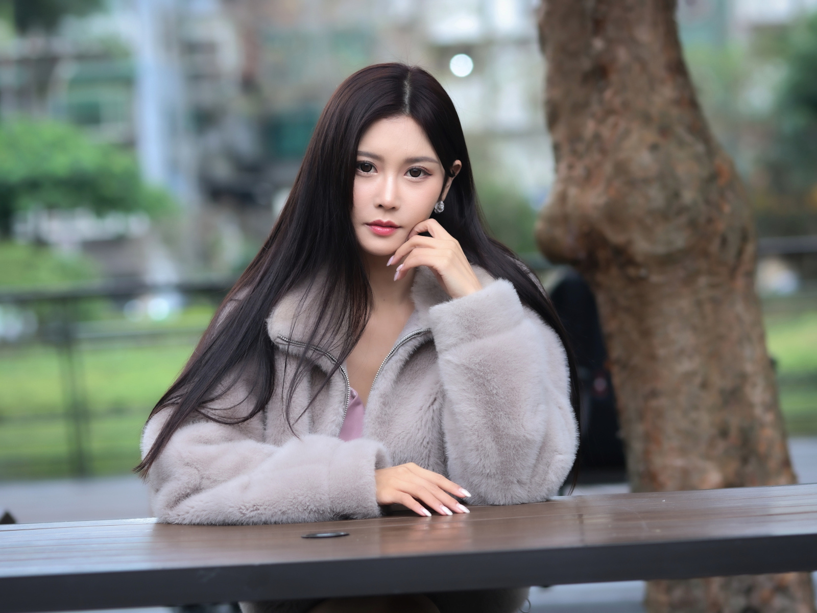 Кареглазая азиатка сидит в парке за столом