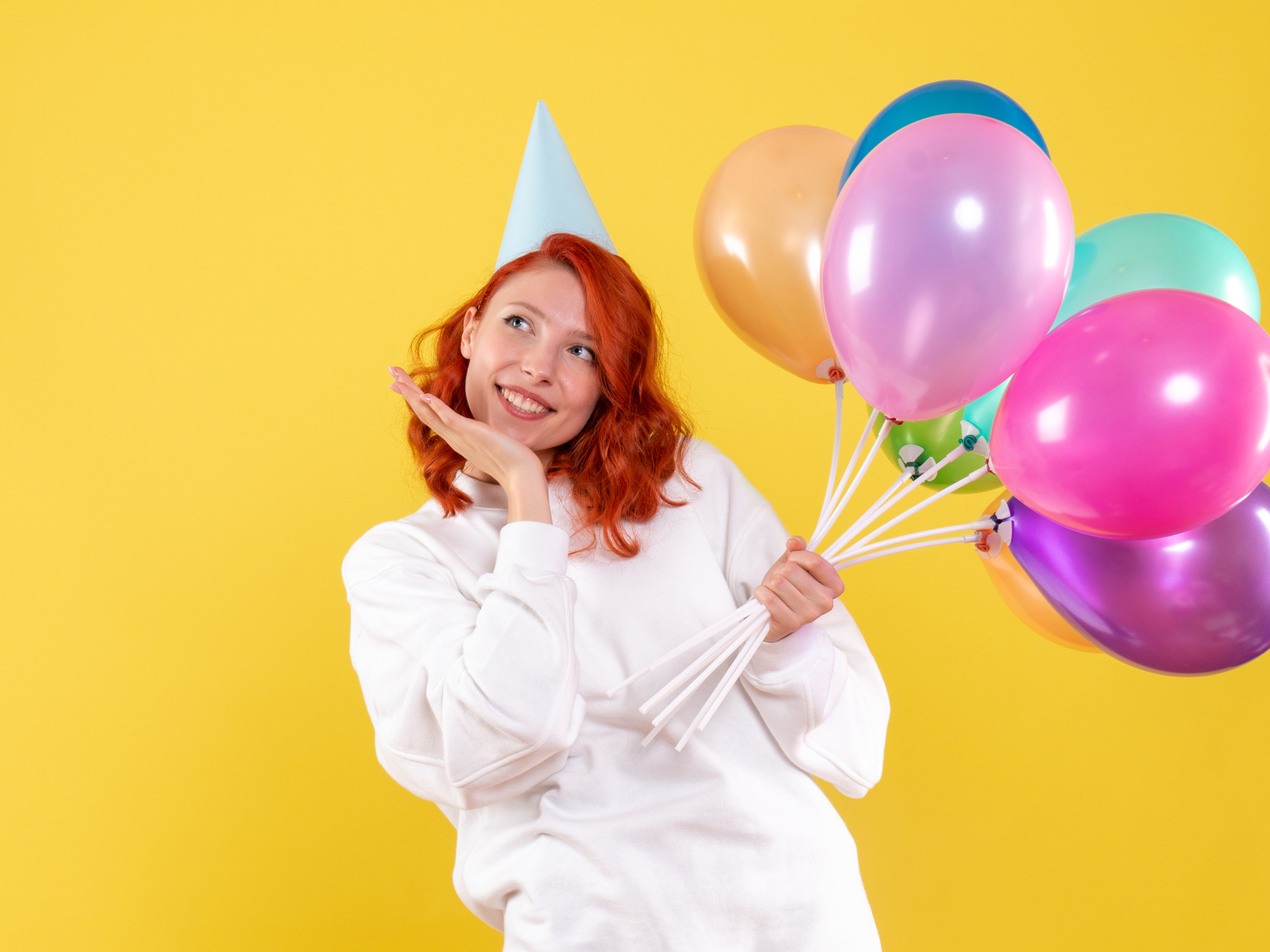 Милая рыжеволосая девушка с шариками на желтом фоне