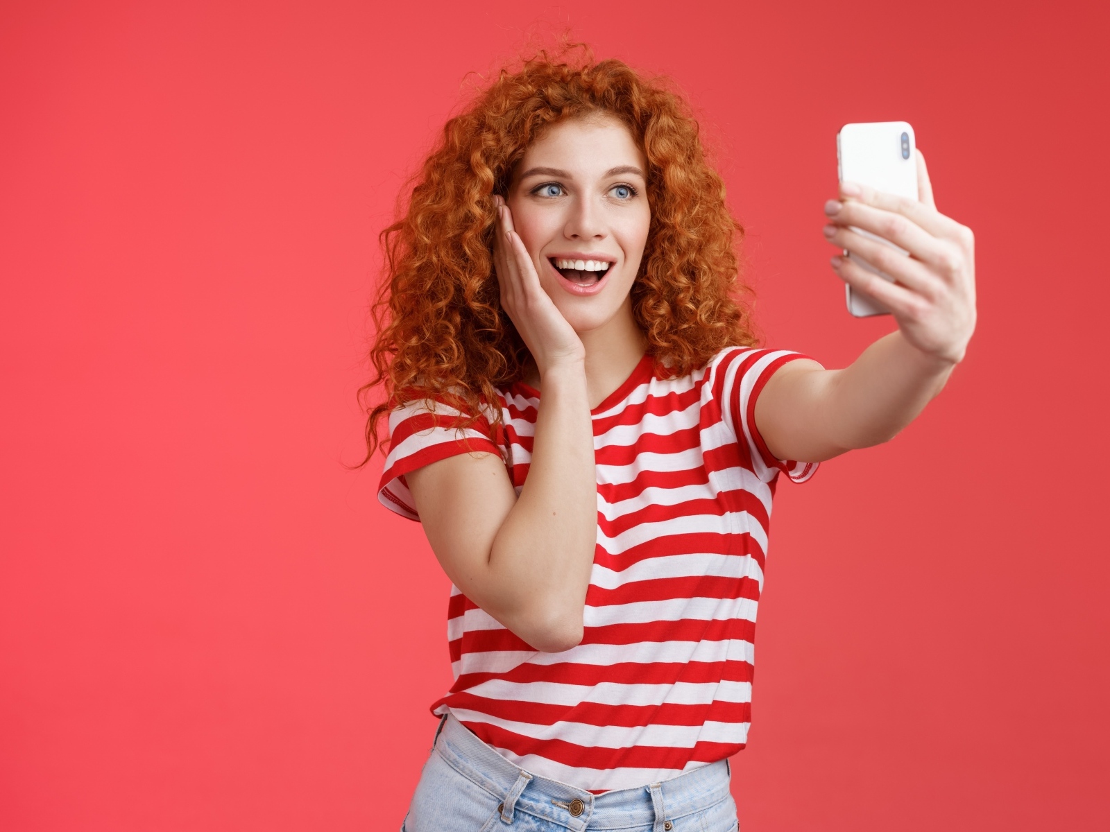 Девушка делает селфи на красном фоне