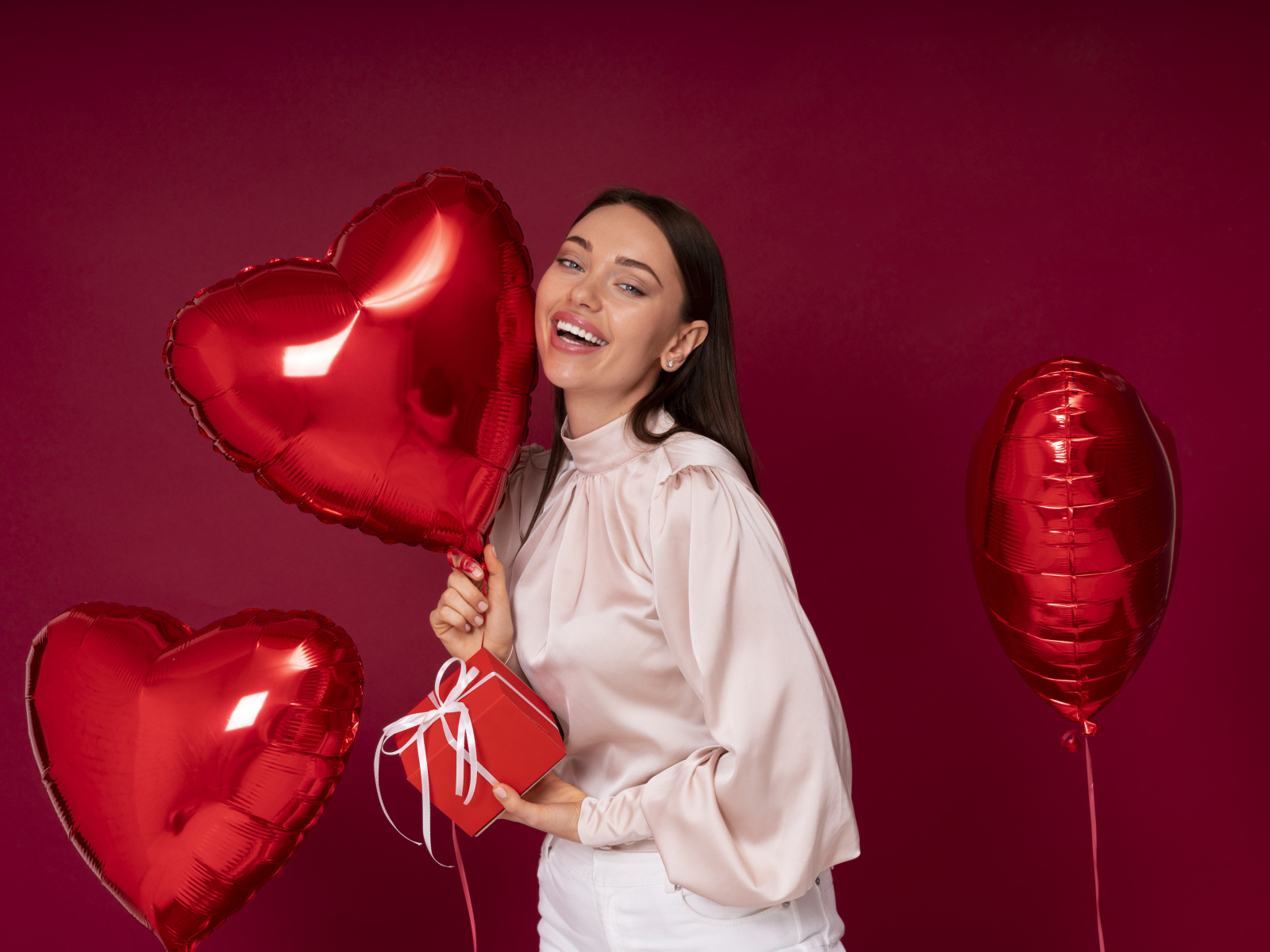 Девушка с шарами в форме сердца на красном фоне