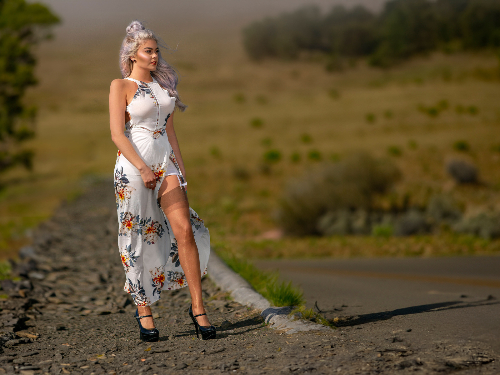 Длинноногая красивая девушка в платье у дороги