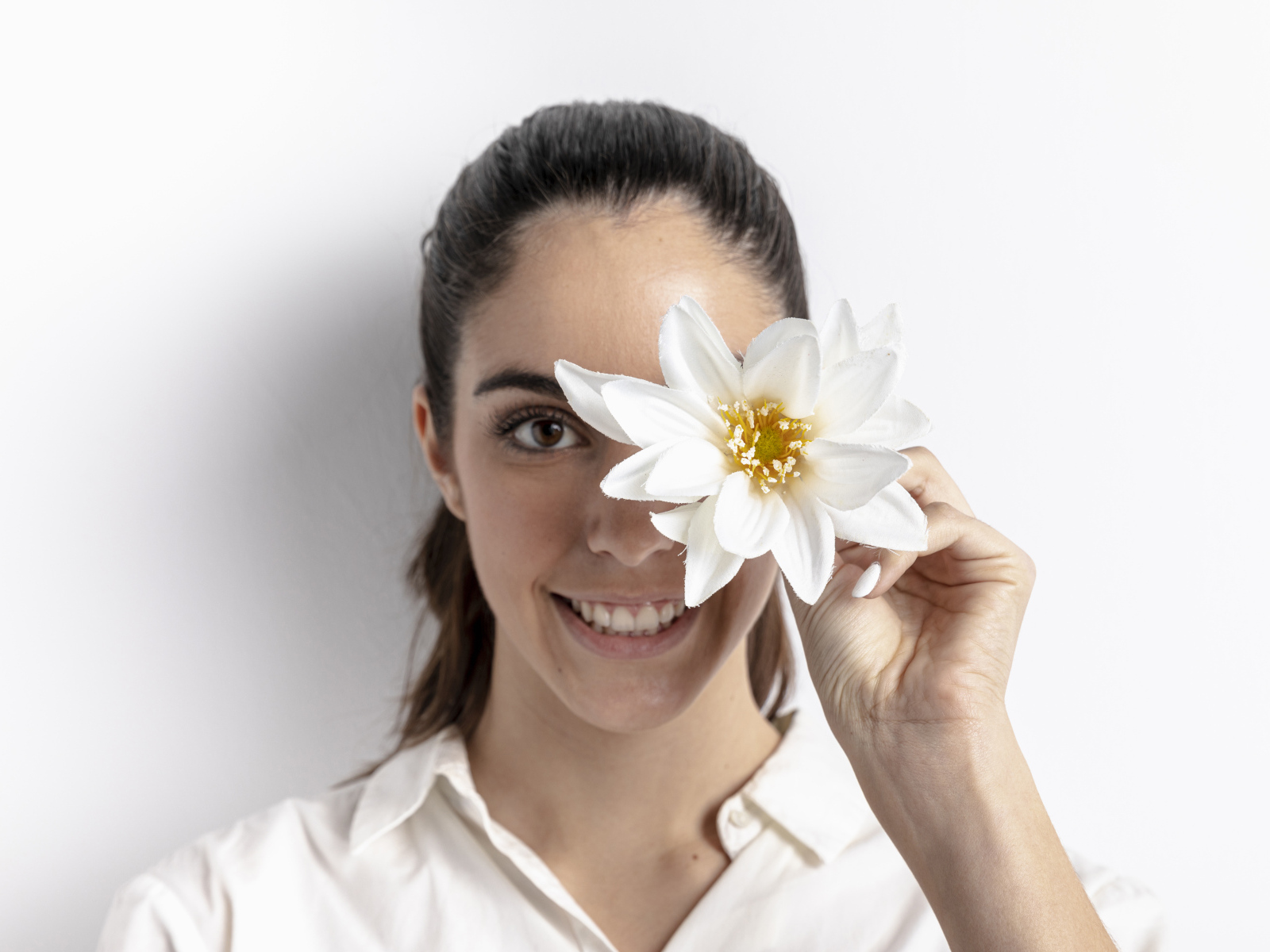 Улыбающаяся девушка закрыла глаз цветком