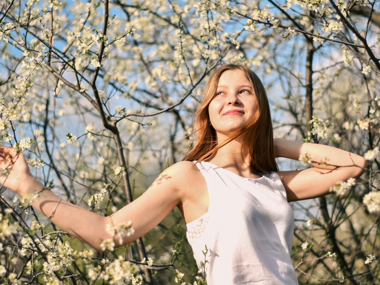 Молодая девушка у цветущего дерева весной