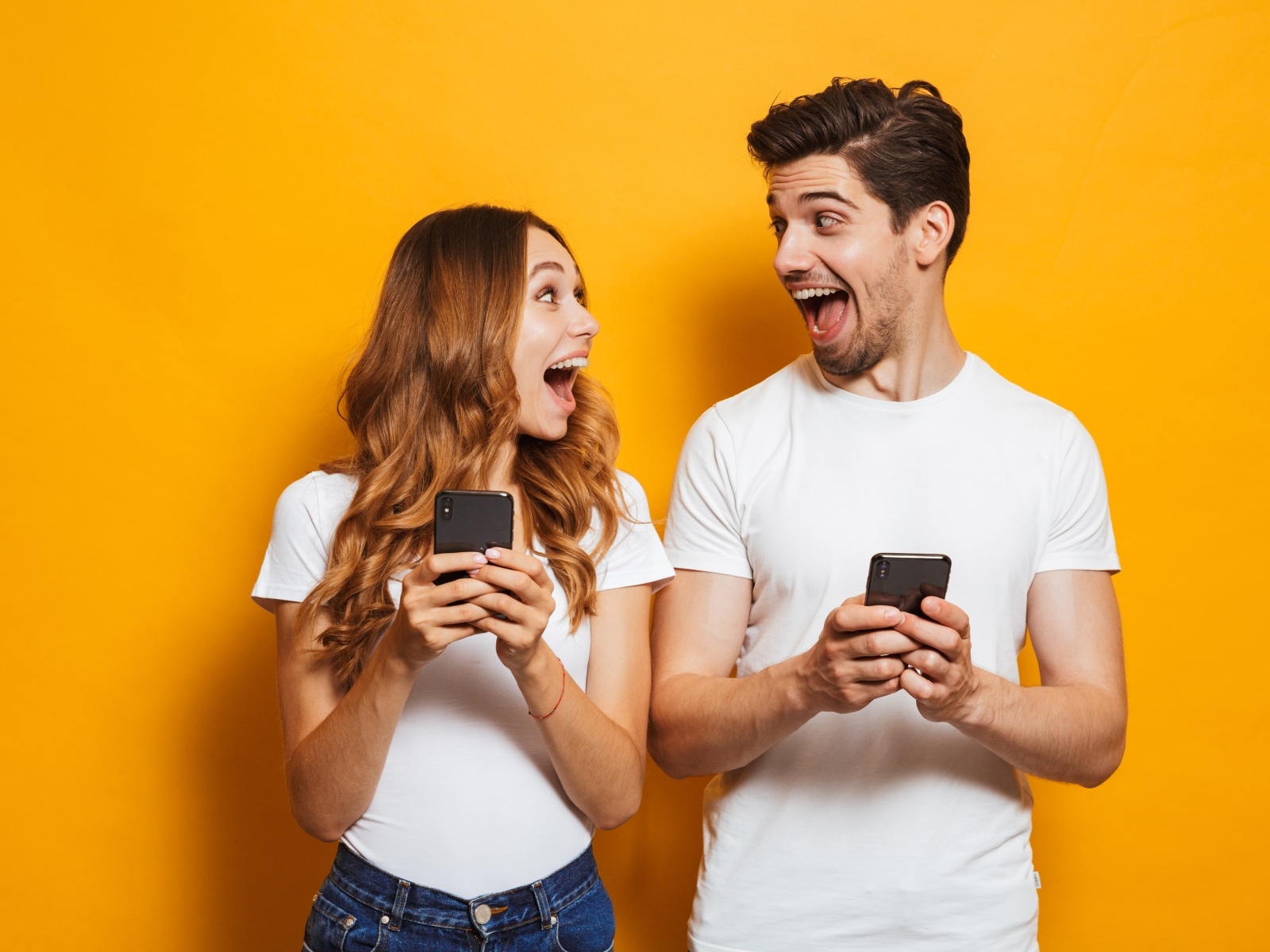 Счастливые парень и девушка с мобильными телефонами