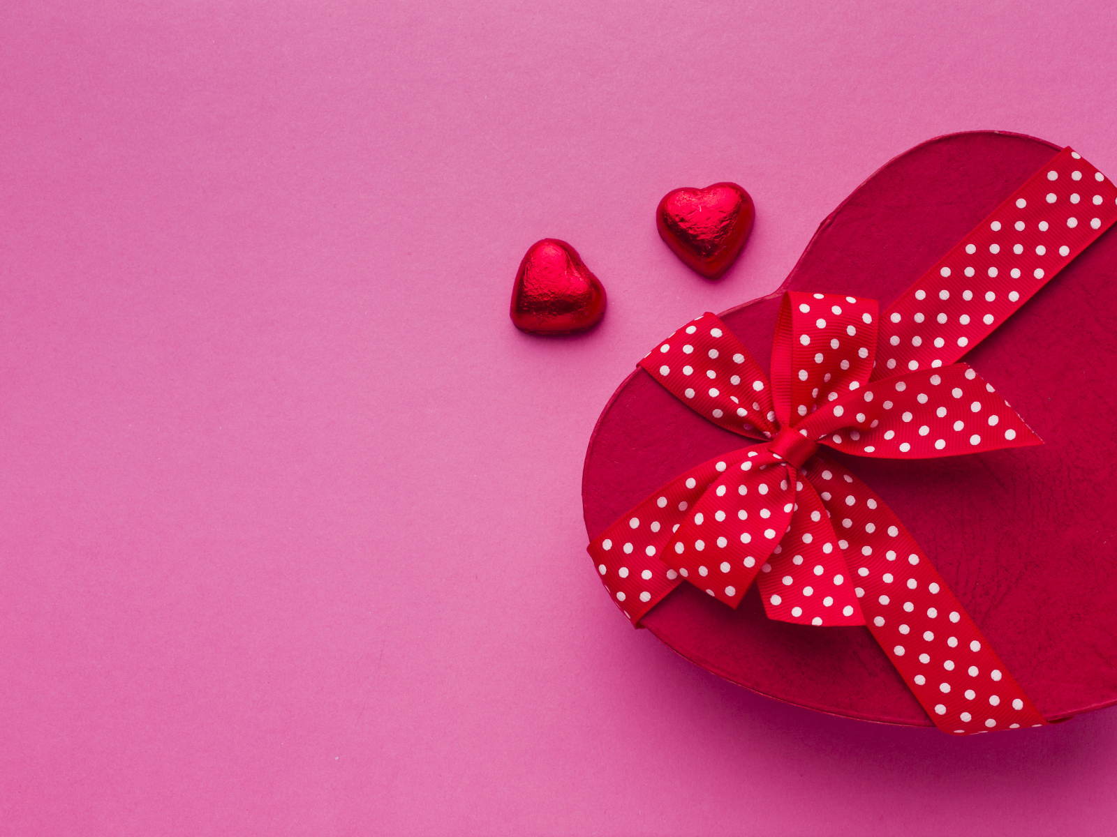 Большая красная коробка в форме сердца на розовом фоне