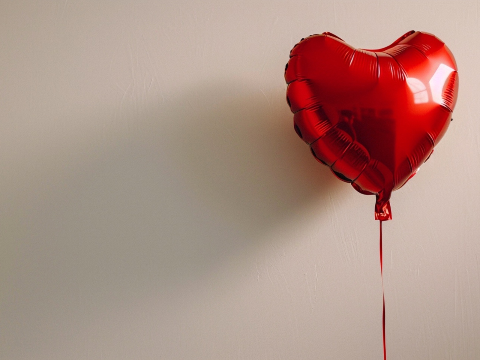 Красный шарик в форме сердца на сером фоне