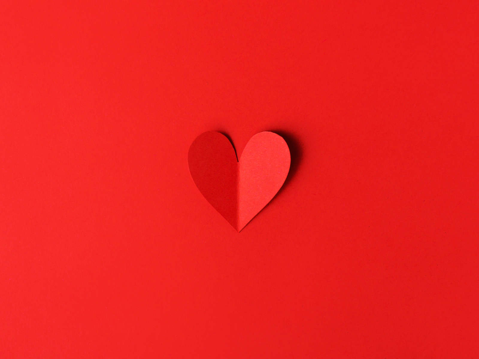 Маленькое бумажное сердце на красном фоне