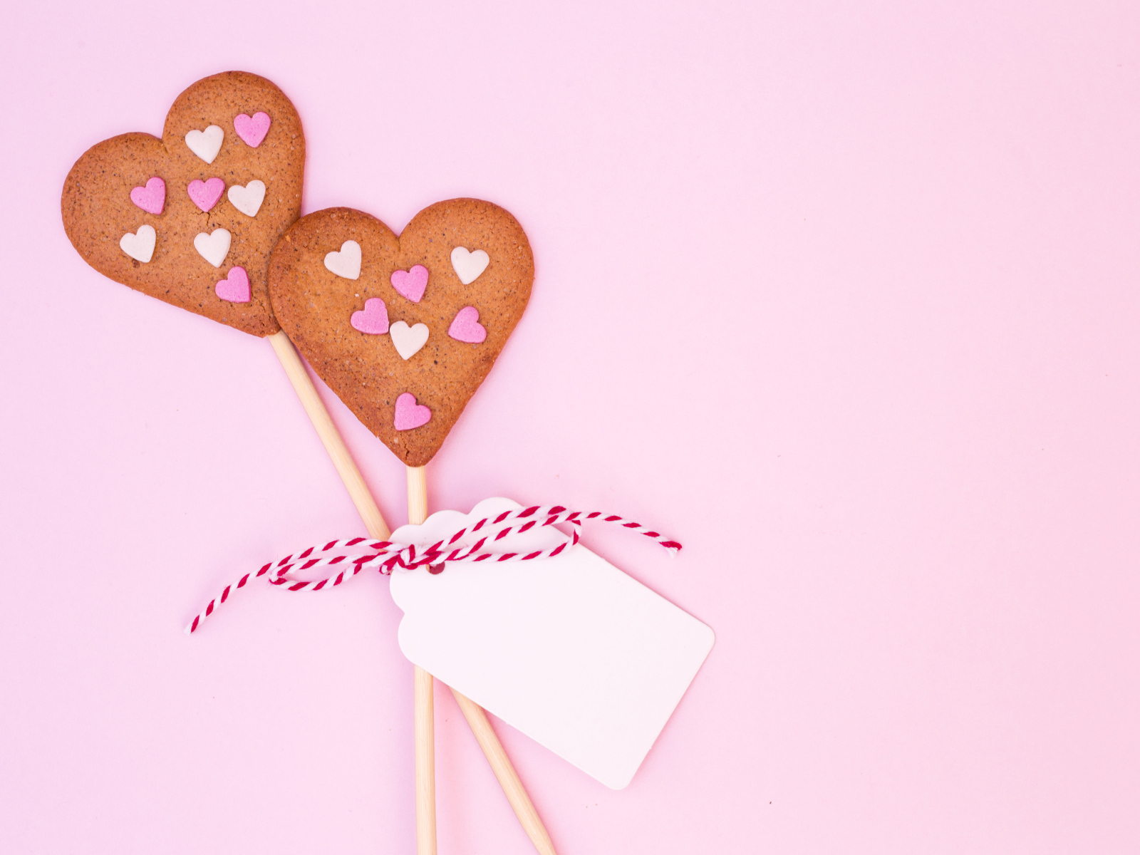 Два сердечка на палочке на розовом фоне