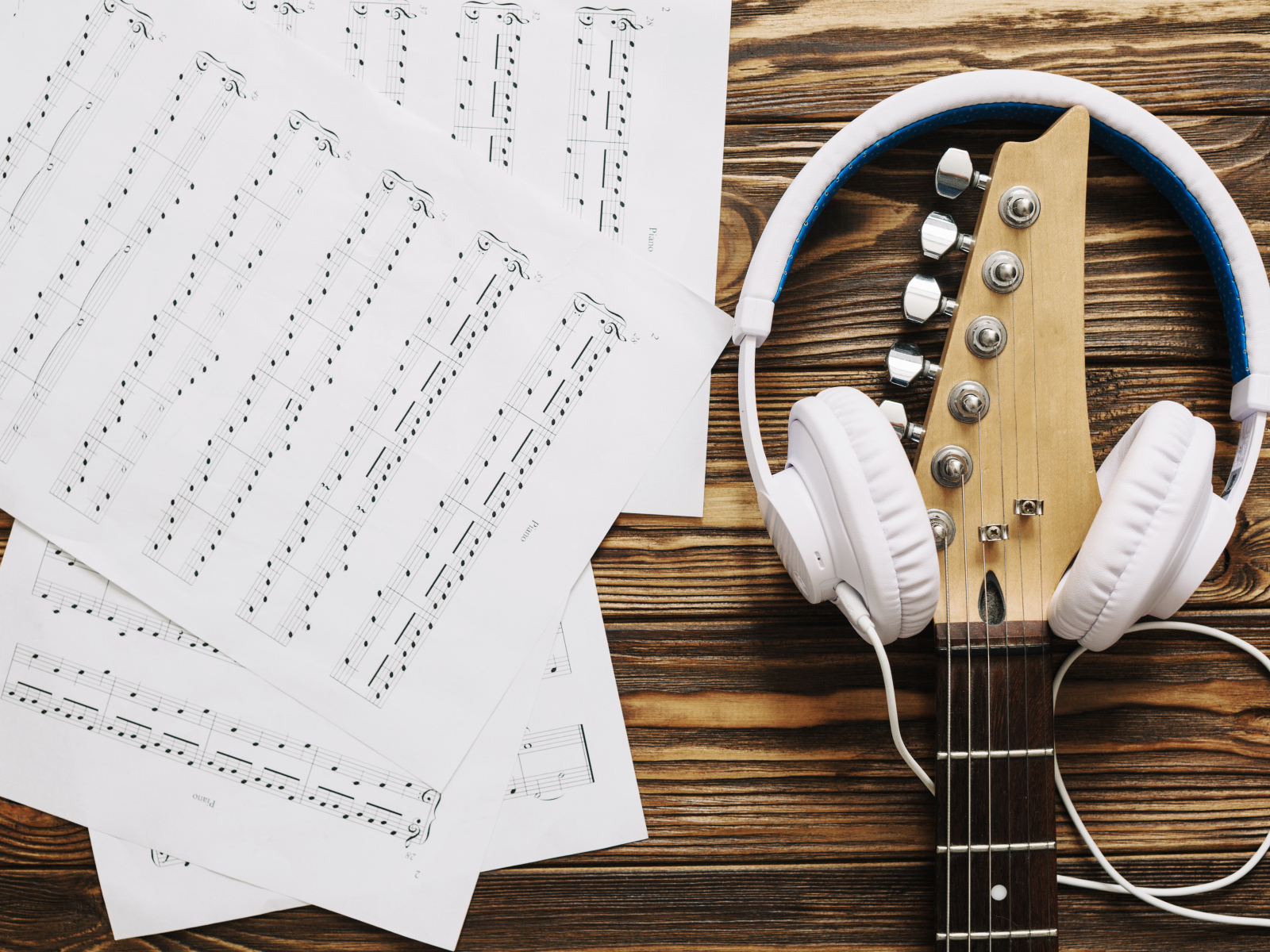 Ноты, наушники и гитара на столе