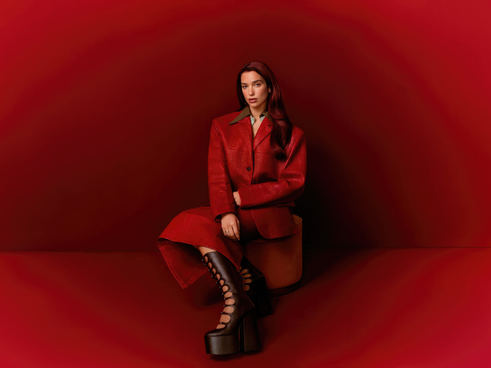 Певица Дуа Липа позирует на красном фоне