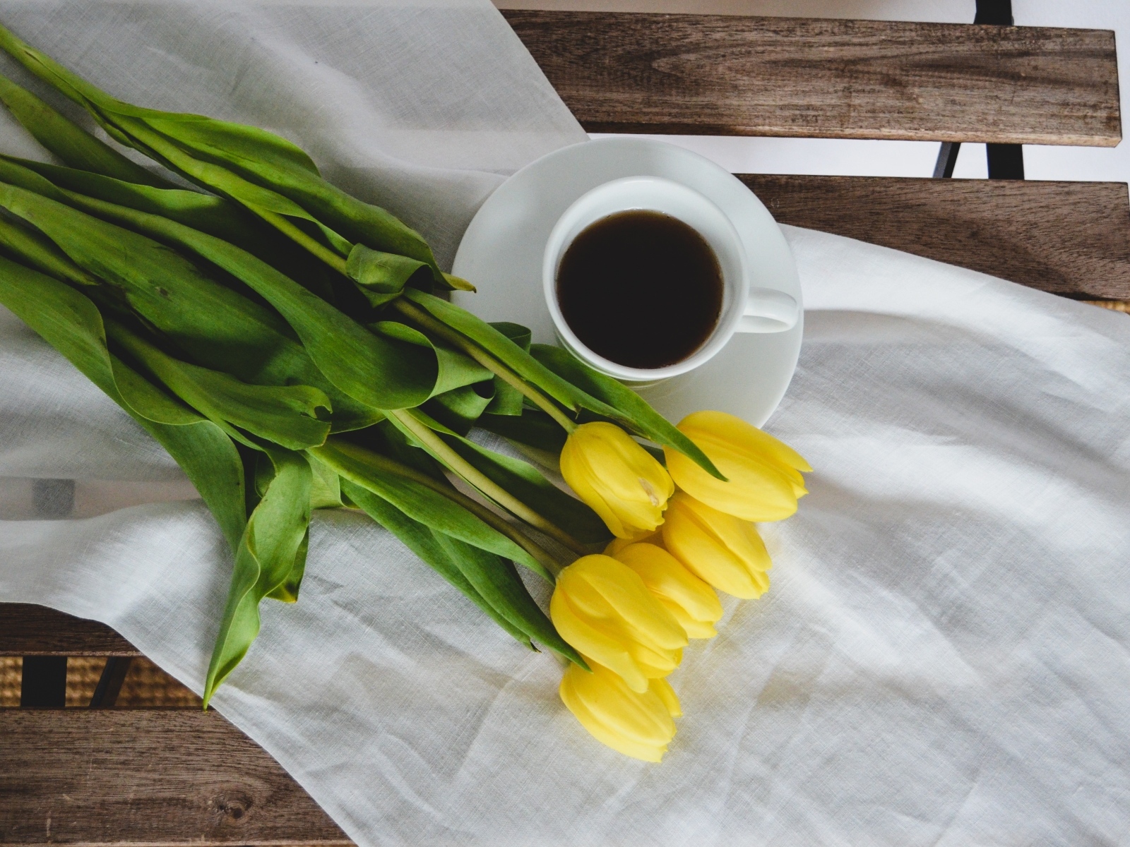 Букет желтых тюльпанов с чашкой кофе на лавке