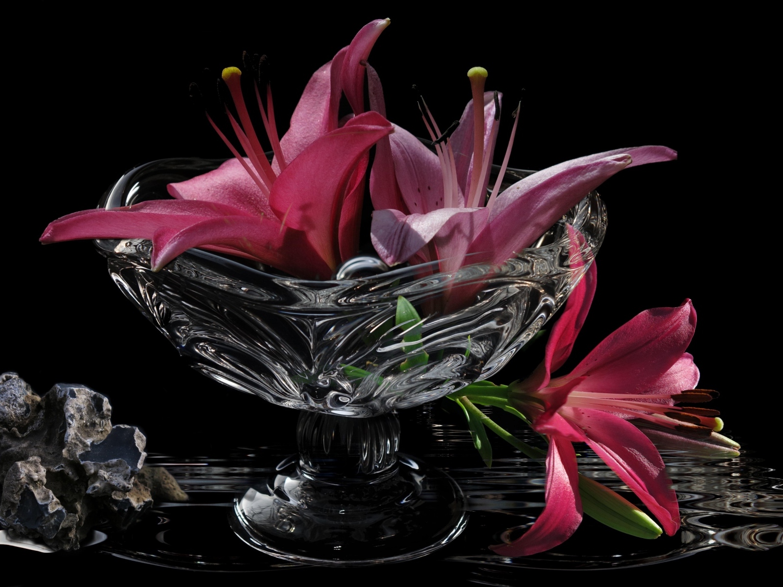 Розовые лилии в стеклянной вазе на столе