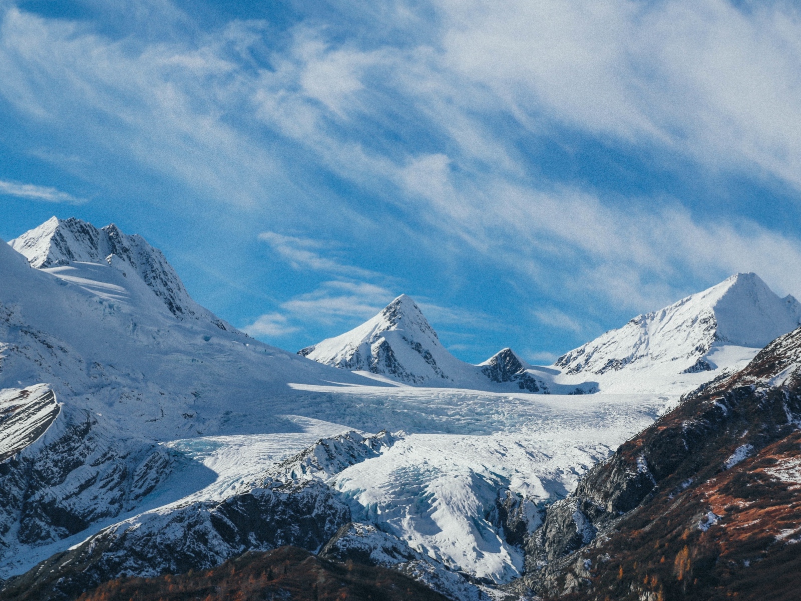 Высокие заснеженные горы под голубым ясным небом