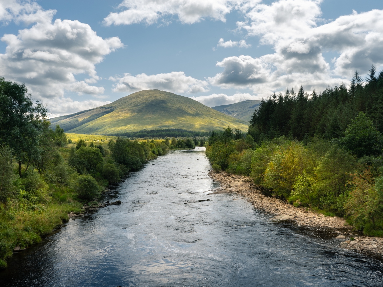 Белые облака в голубом небе над рекой в горах