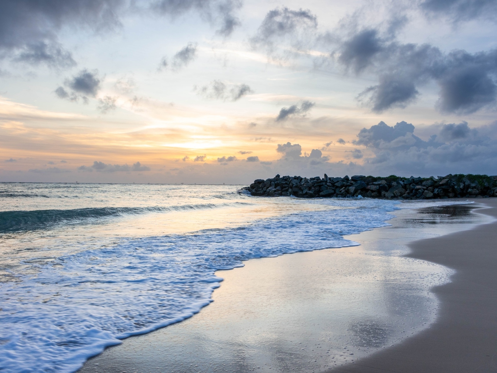 Волны омывают морской песок на рассвете