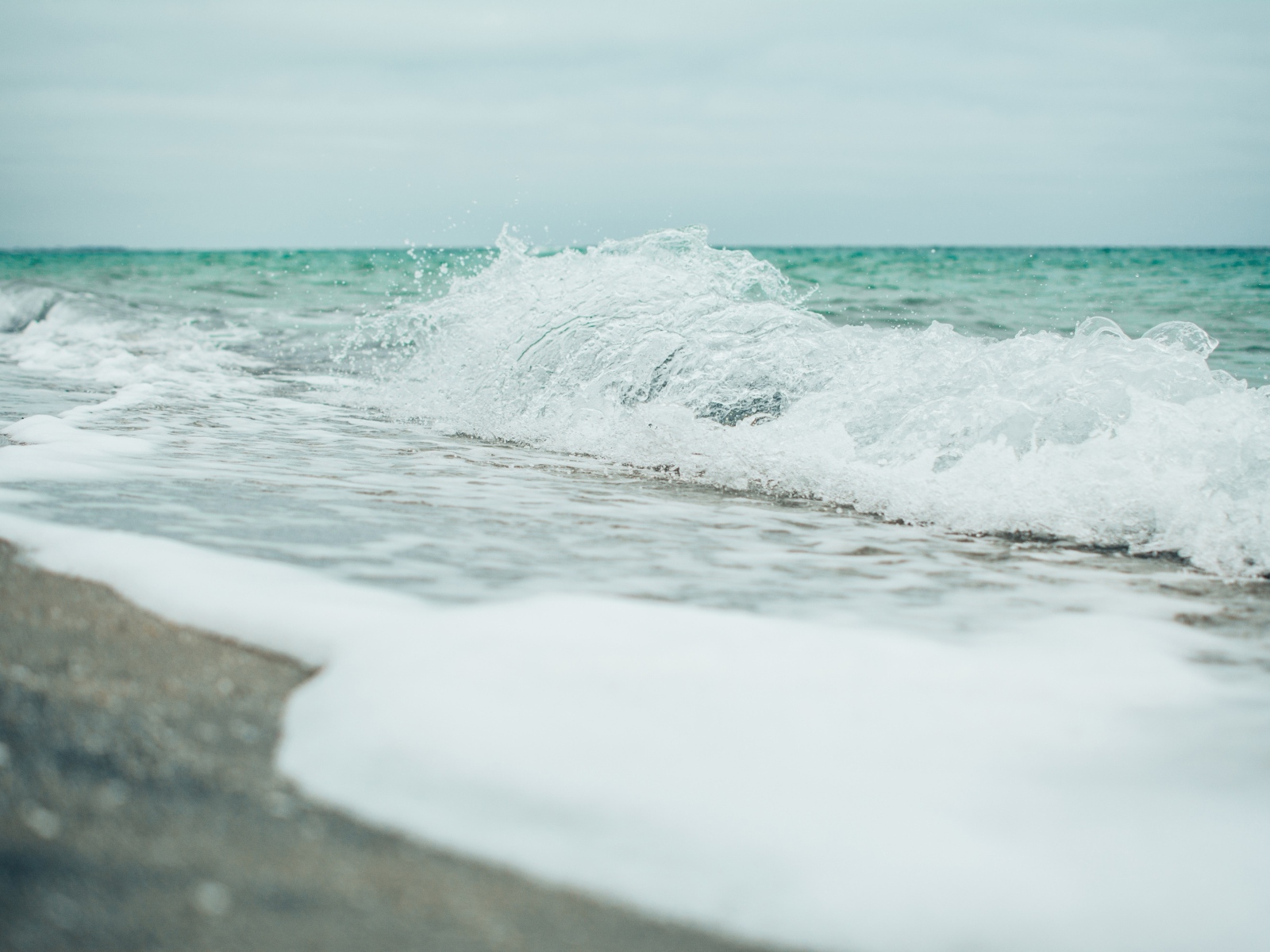 Белая морская пена на морском песке вблизи